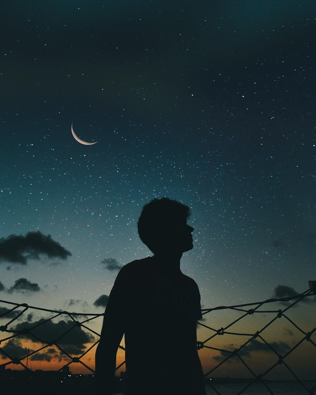 A lone silhouette stands beneath a crescent moon and starry sky, evoking a sense of solitude and wonder. A lone silhouette stands beneath a crescent moon and starry sky, evoking a sense of solitude and wonder.