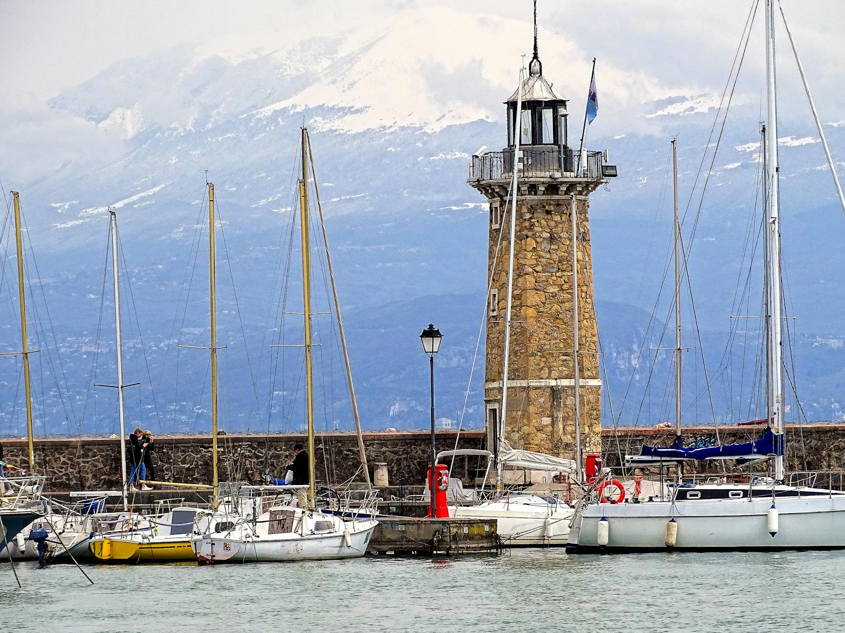 Captivating view of Desenzano del Garda harbor featuring the iconic lighthouse and moored sailboats.