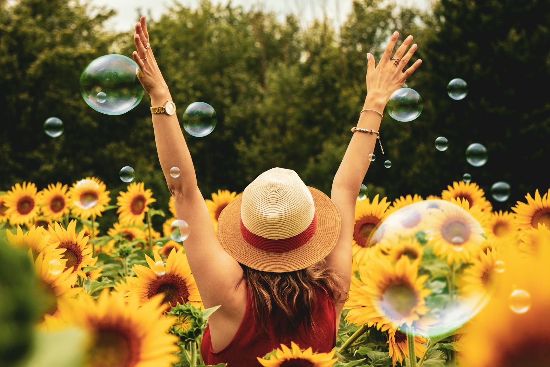 A joyful woman in a sunflower field with bubbles, expressing…