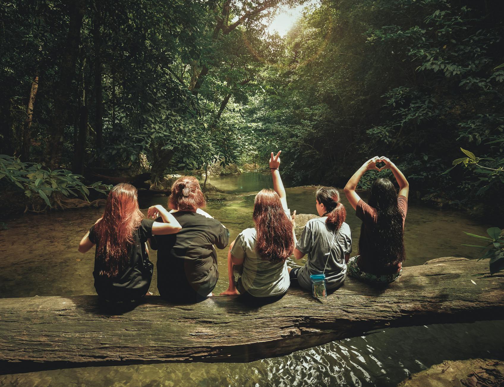 Five women enjoying nature on a log by a river in the forest, Tambon Ban Tai, Thailand. Five women enjoying nature on a log by a river in the forest, Tambon Ban Tai, Thailand.