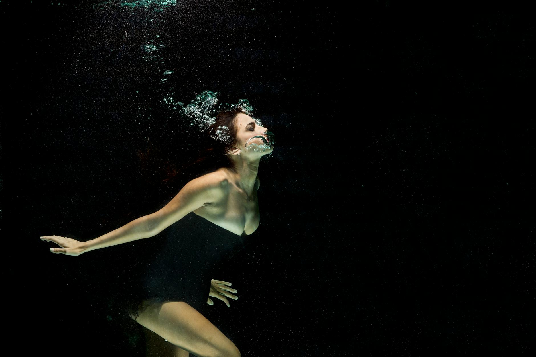Artistic underwater shot of a woman in black dress with bubbles. Artistic underwater shot of a woman in black dress with bubbles.
