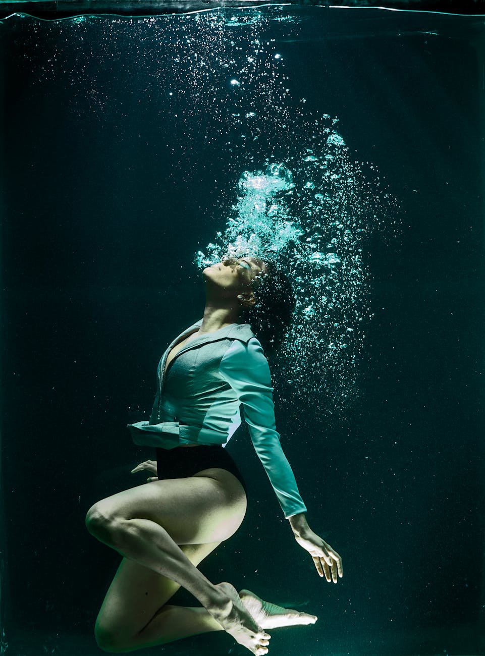 Dramatic photo of a woman diving underwater in stylish attire. Dramatic photo of a woman diving underwater in stylish attire.