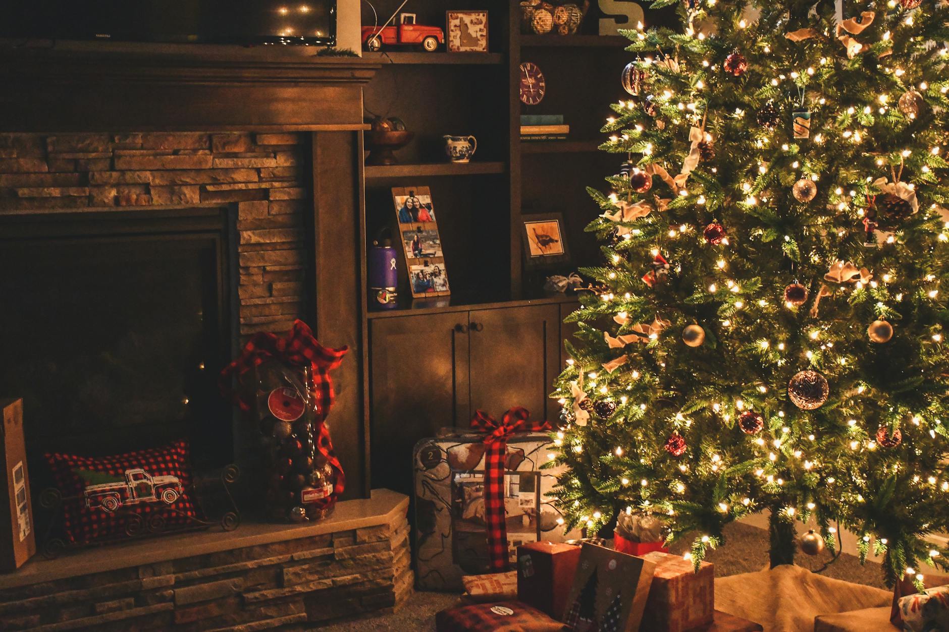 Warm holiday scene of a decorated Christmas tree with gifts by a cozy fireplace. Warm holiday scene of a decorated Christmas tree with gifts by a cozy fireplace.