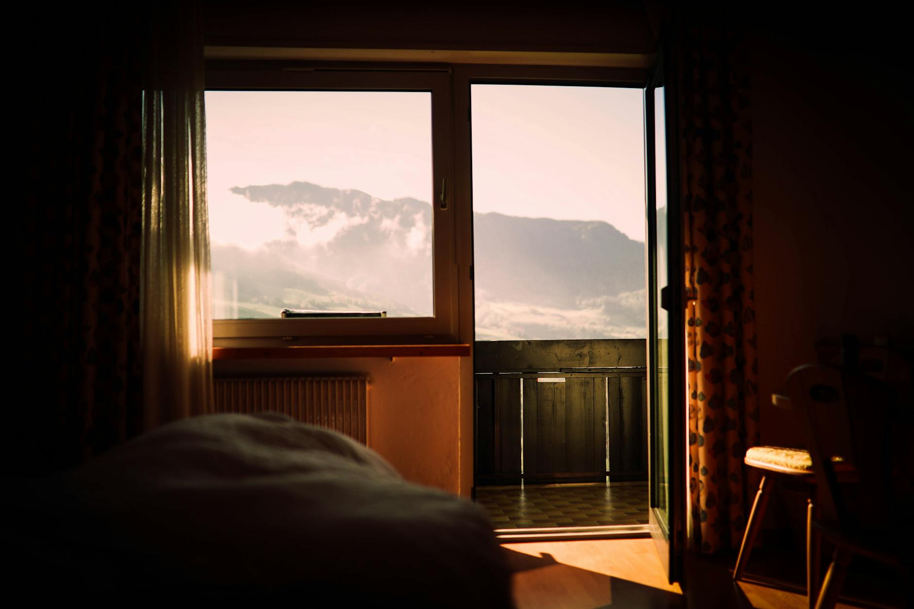 A cozy bedroom with a stunning mountain view through the window at sunset.