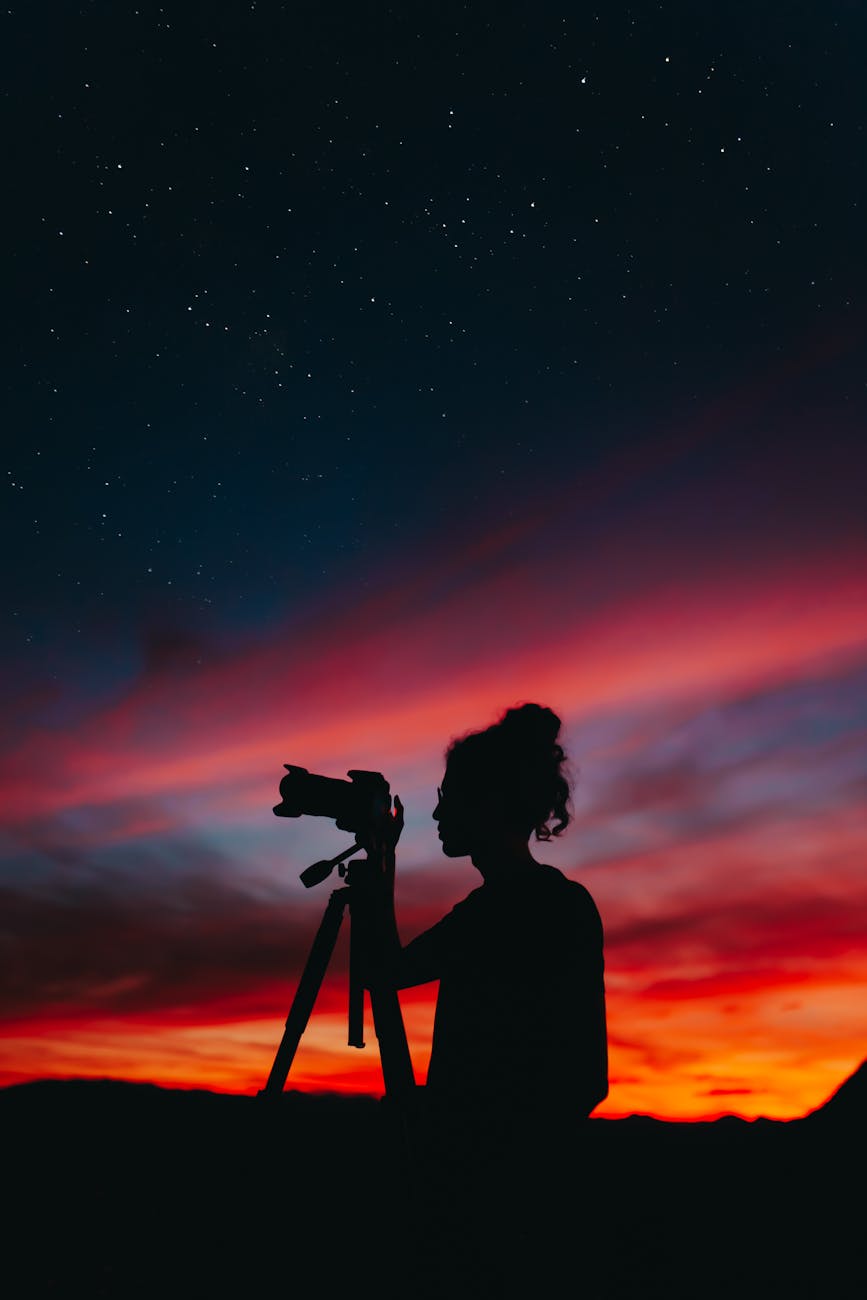 Silhouette of a photographer capturing the starry sky during a colorful sunset, creating a dramatic and artistic scene. Silhouette of a photographer capturing the starry sky during a colorful sunset, creating a dramatic and artistic scene.