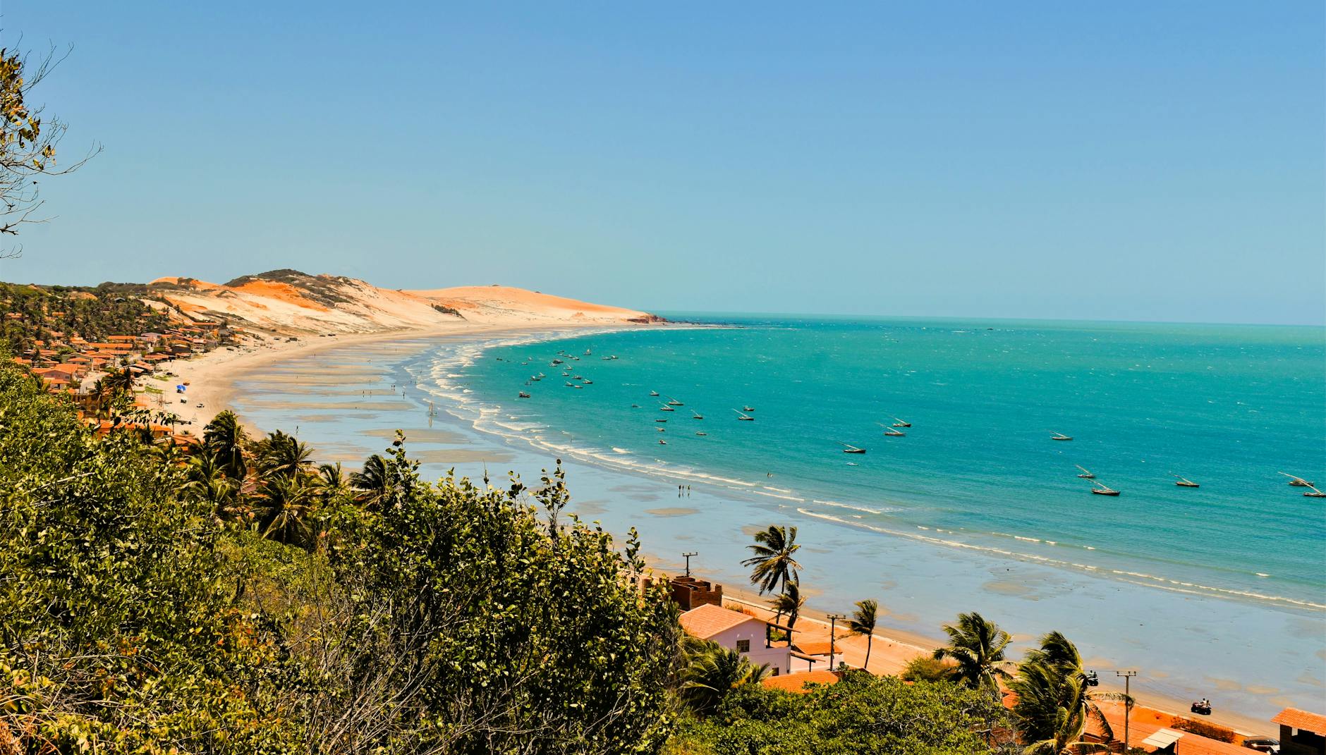 Beautiful coastline with sand dunes and turquoise sea under a clear sky.