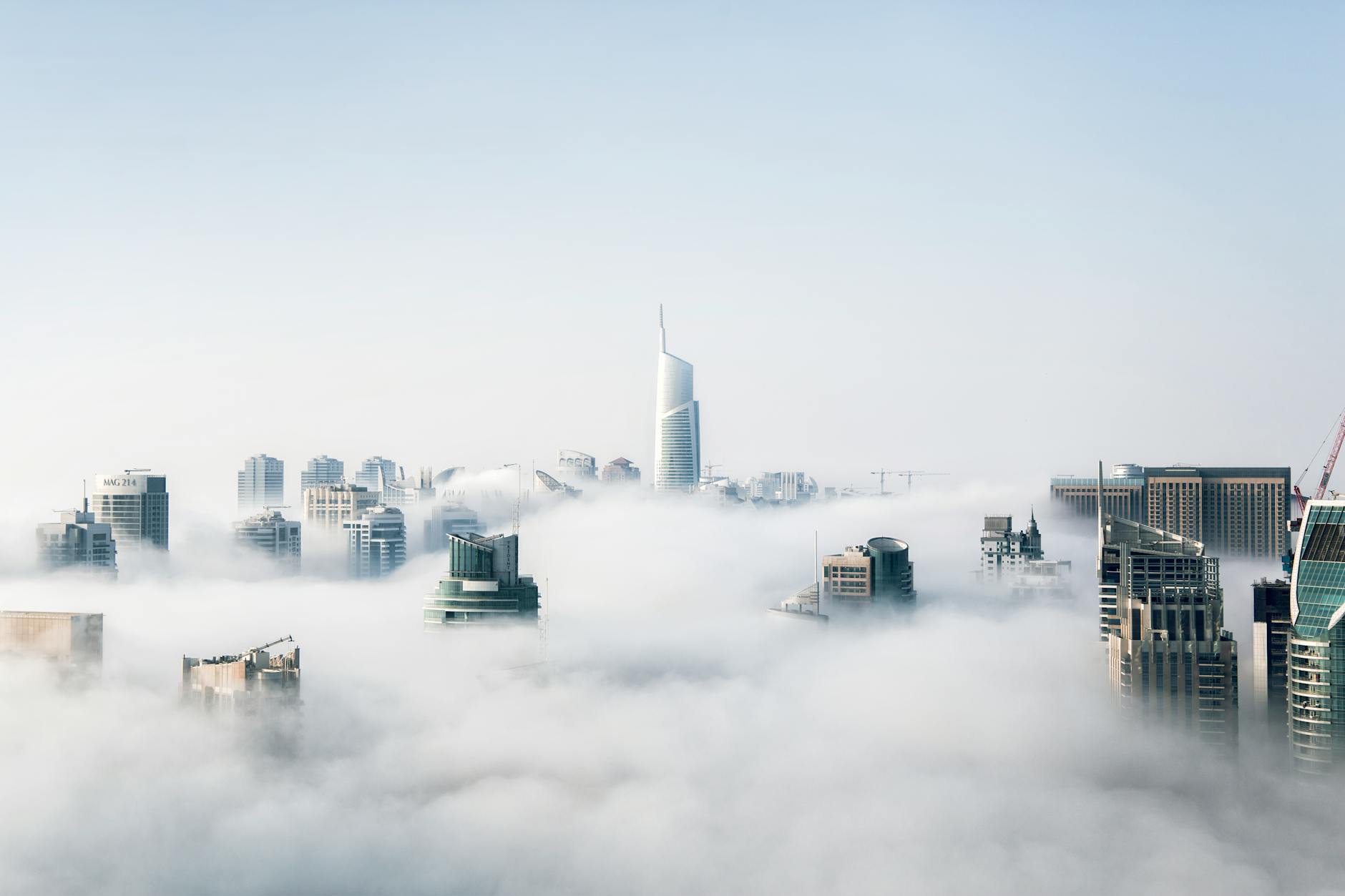 A stunning view of Dubai skyscrapers emerging through a blanket of fog, showcasing modern architecture. A stunning view of Dubai skyscrapers emerging through a blanket of fog, showcasing modern architecture.