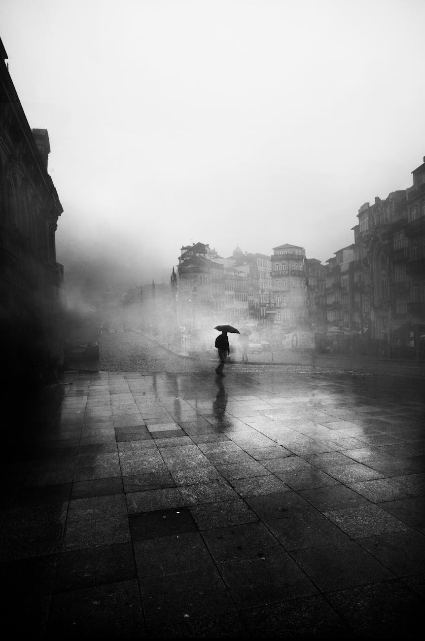 A lone figure with an umbrella in a foggy city, creating a moody, atmospheric scene.
