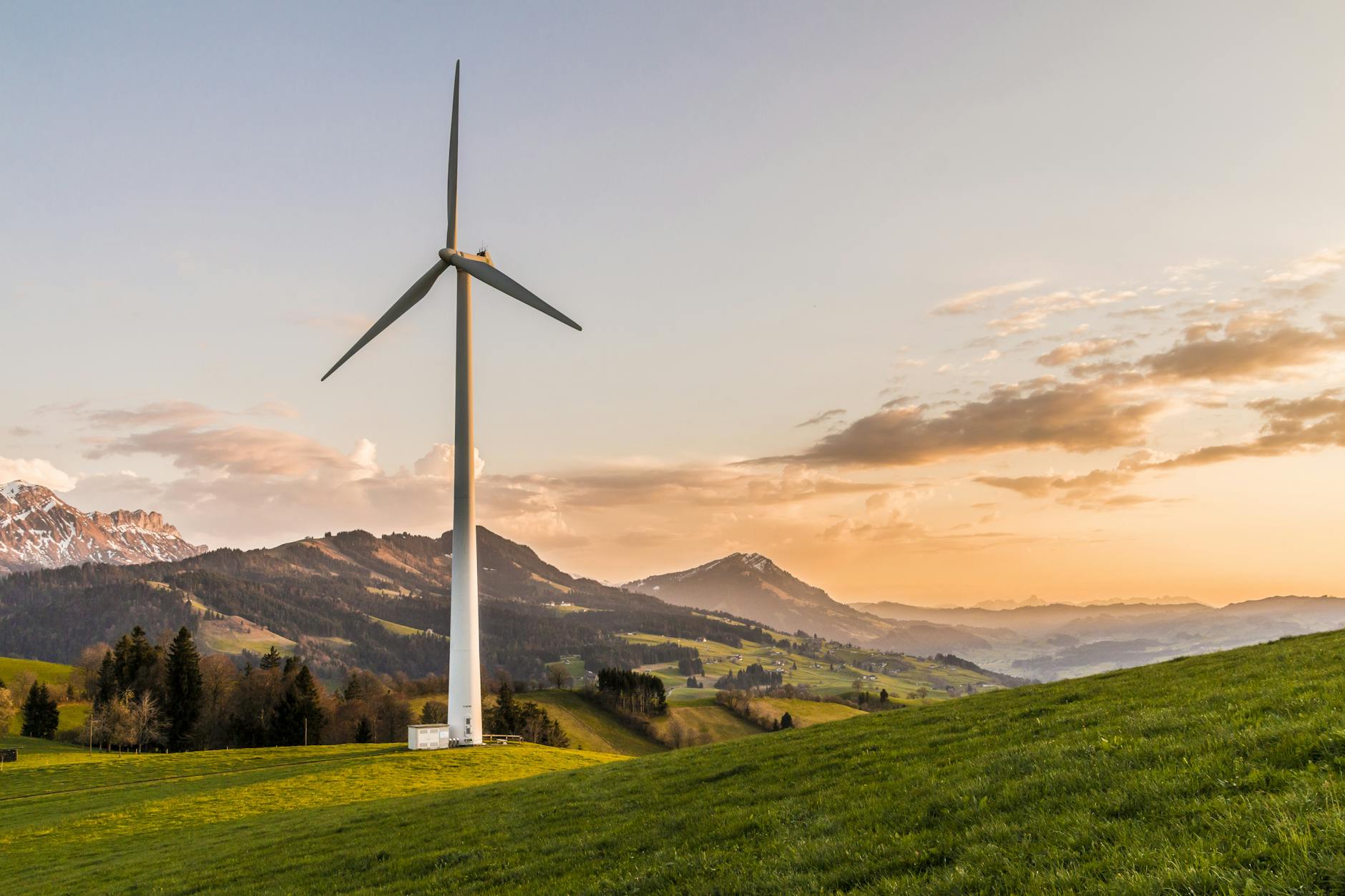 Wind turbine amid rolling hills and mountains at sunset, symbolizing renewable energy and sustainability. Wind turbine amid rolling hills and mountains at sunset, symbolizing renewable energy and sustainability.