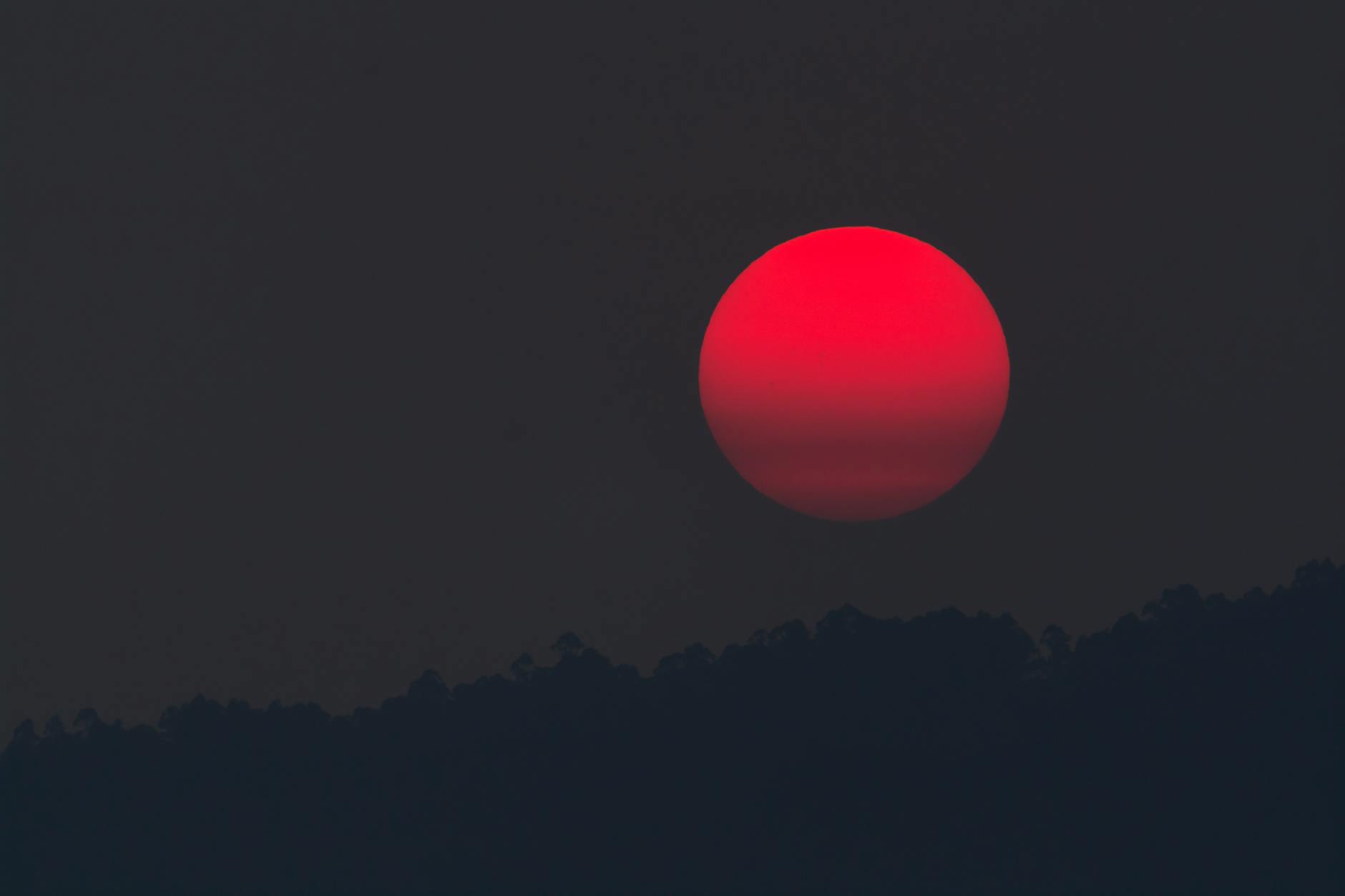 A captivating blood moon rising over a silhouette of hills, capturing the beauty of twilight. A captivating blood moon rising over a silhouette of hills, capturing the beauty of twilight.