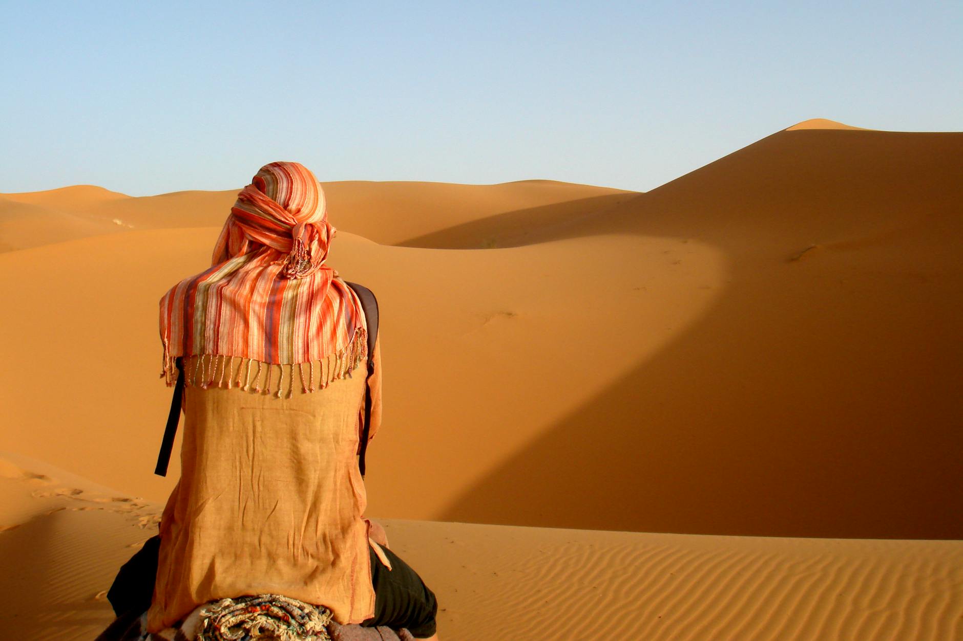 Traveler viewed from behind, admiring Morocco’s striking sand dunes.