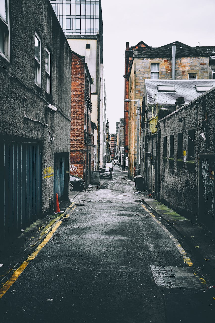 Quiet urban alley with parked cars between old brick buildings,…