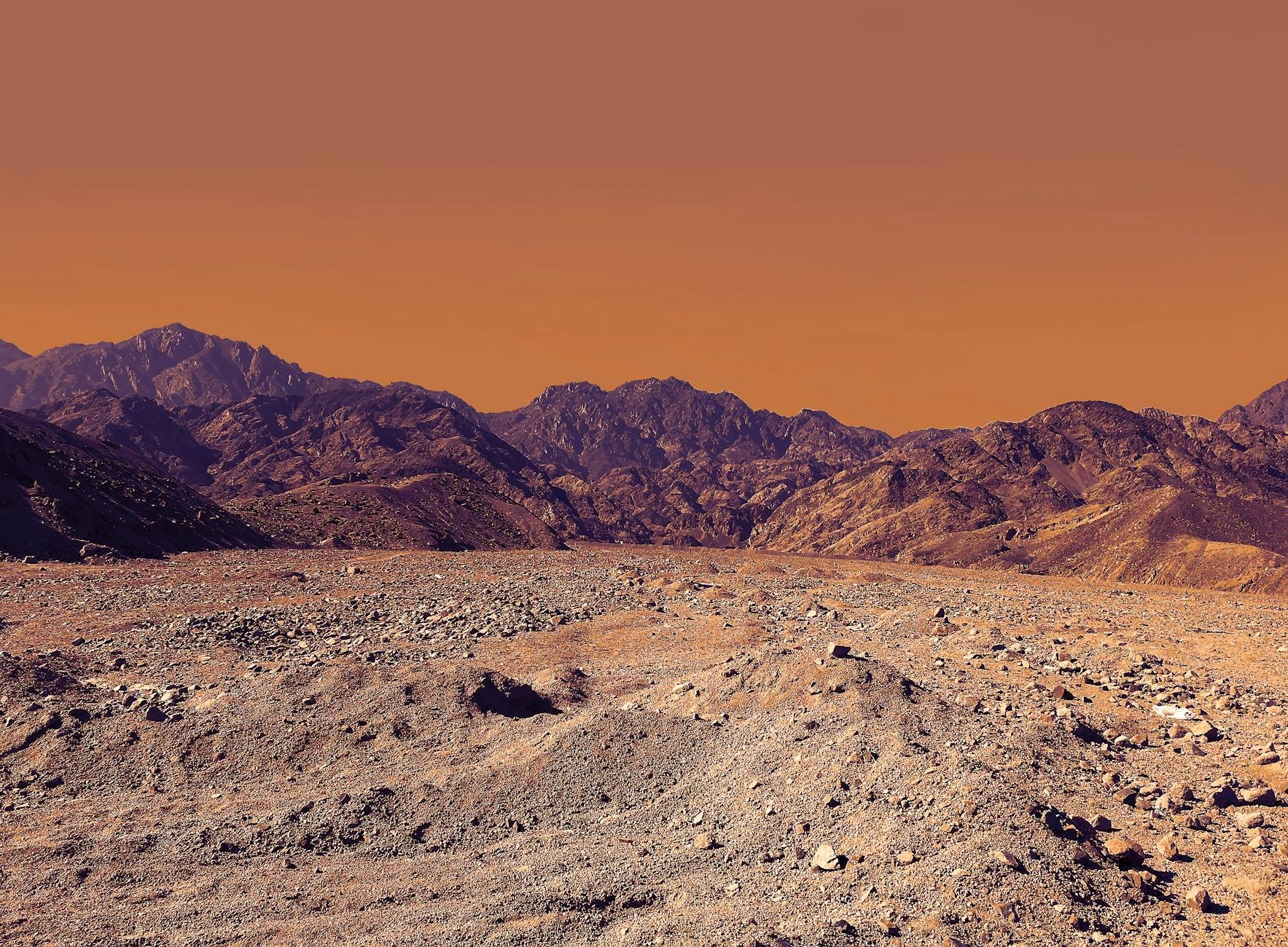Stunning landscape of South Sinai’s rocky desert under a vibrant orange sky.