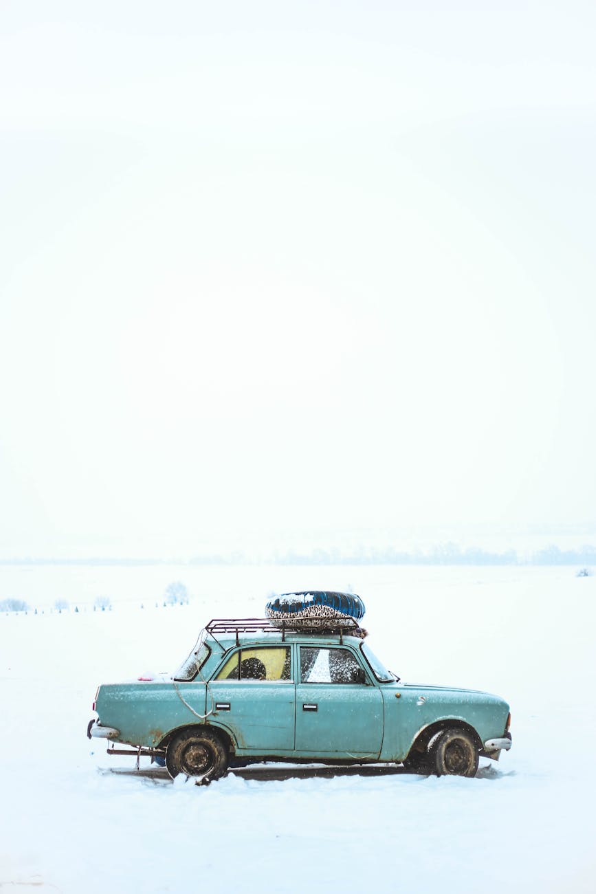A vintage car parked in a snowy field in Kyrgyzstan, capturing the serene winter landscape.