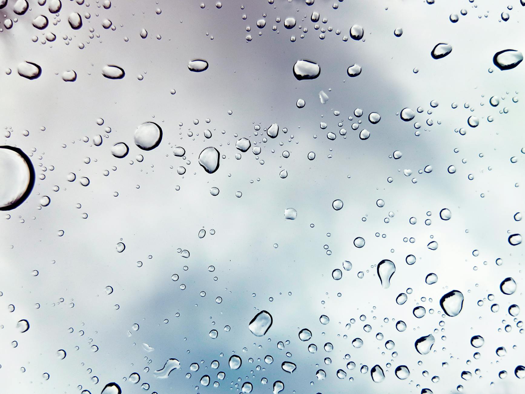 Raindrops on a window against a cloudy sky, creating a peaceful mood. Raindrops on a window against a cloudy sky, creating a peaceful mood.