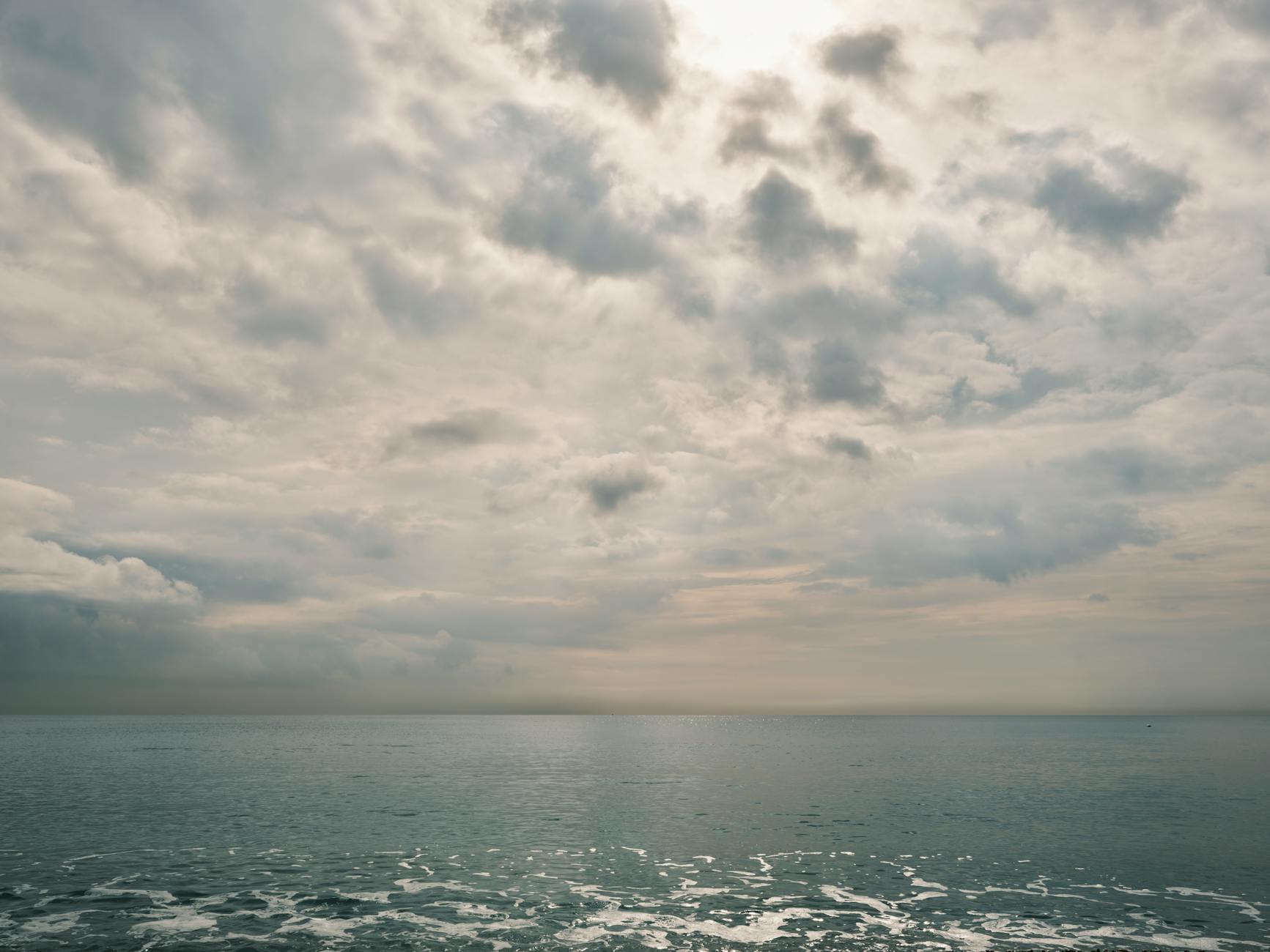 Peaceful view of the ocean under an overcast, cloudy sky creating a tranquil and calming atmosphere.