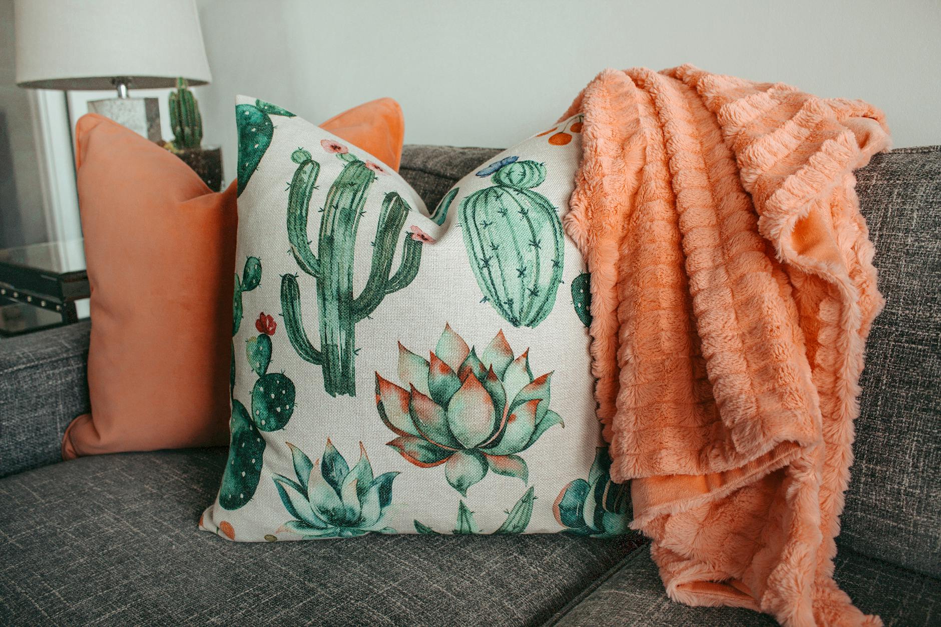 Elegant interior decor featuring cactus-themed pillows and a cozy blanket on a modern couch.