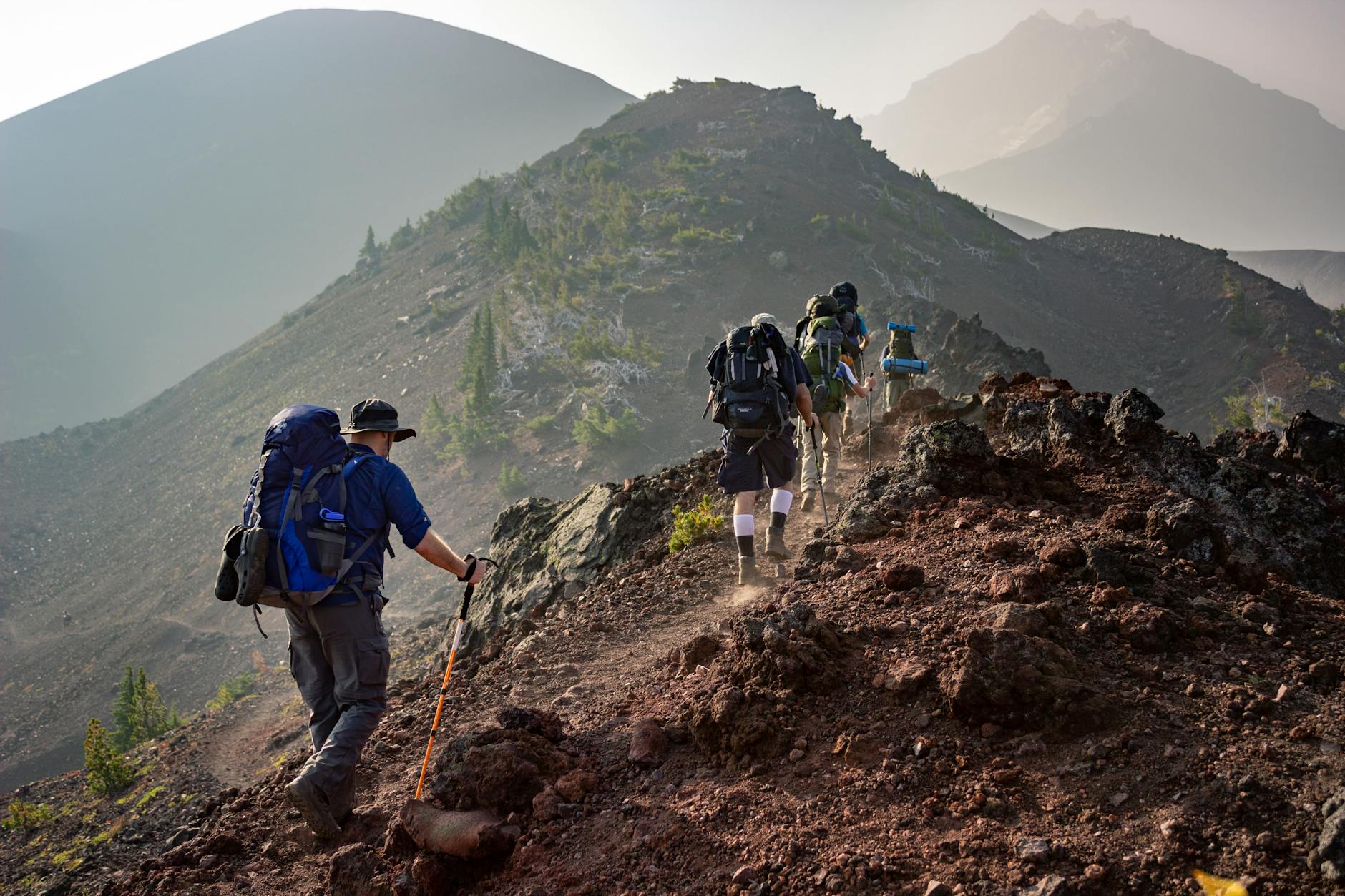 Group of hikers trekking on a rugged mountain trail in Oregon’s scenic outdoors. Group of hikers trekking on a rugged mountain trail in Oregon’s scenic outdoors.