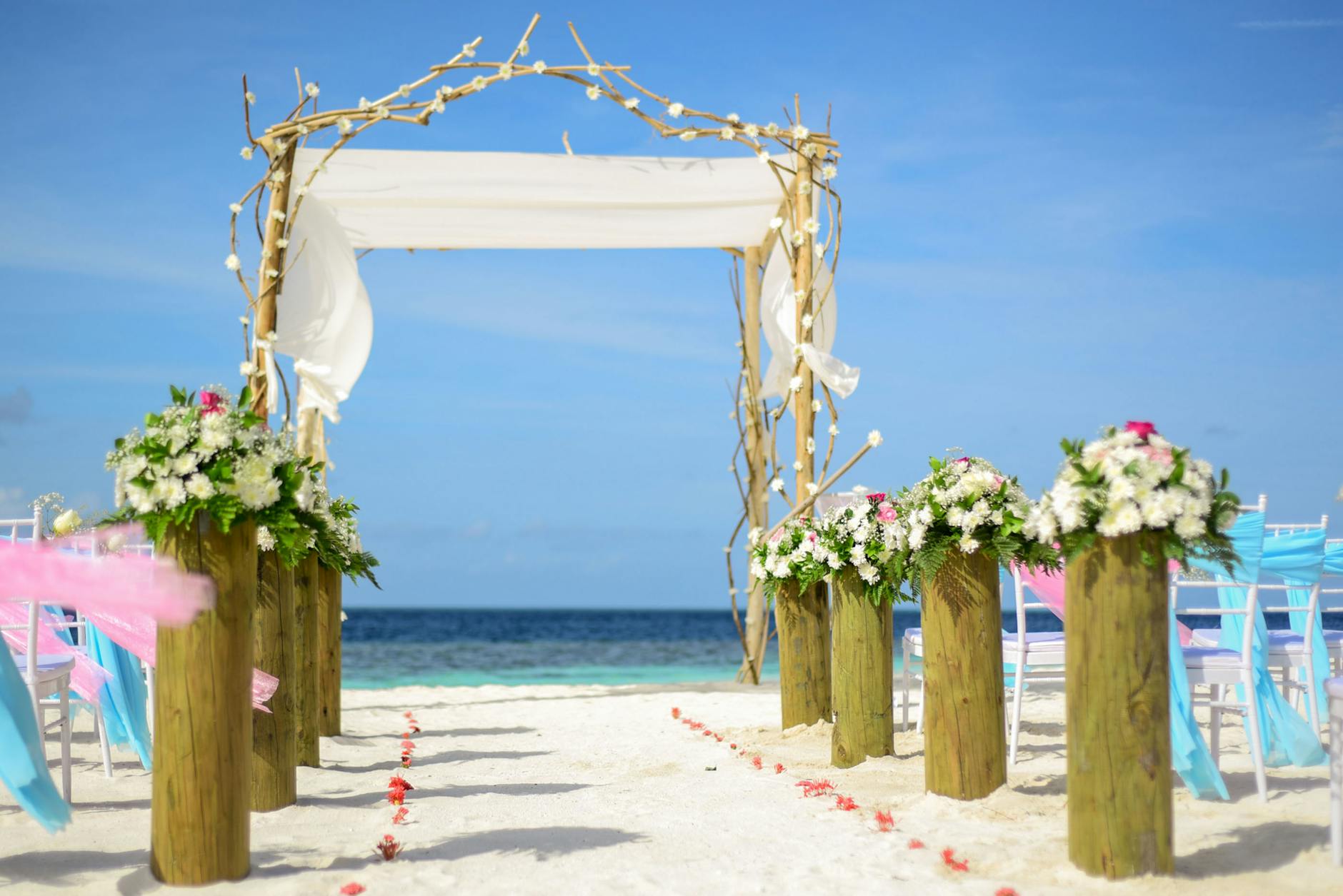 A beautiful beach wedding setup featuring a floral arch and ocean view.