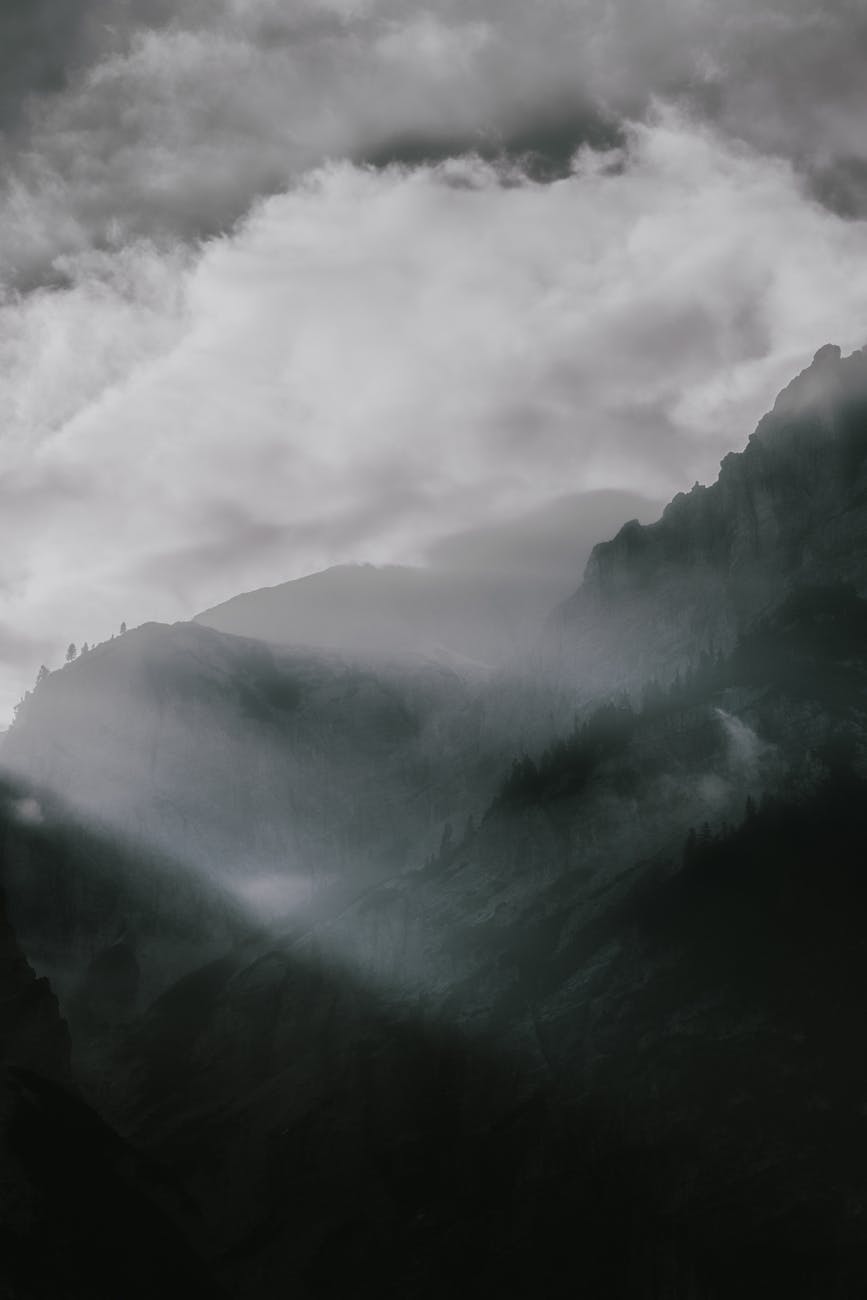 A breathtaking panoramic view of a fog-covered mountain range with dramatic lighting and clouds. A breathtaking panoramic view of a fog-covered mountain range with dramatic lighting and clouds.