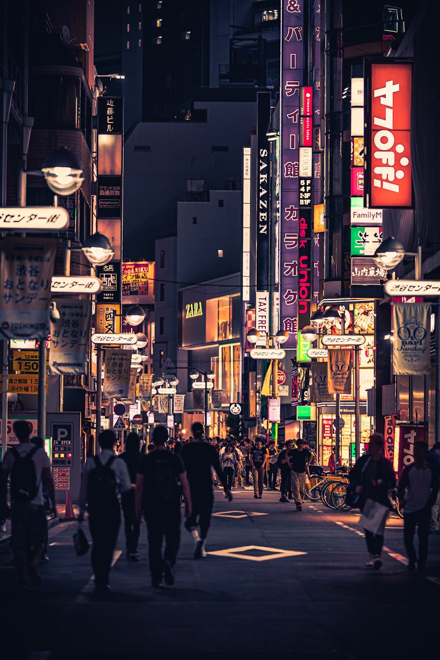 Bustling street in Tokyo at night filled with neon signs and people enjoying the lively atmosphere.