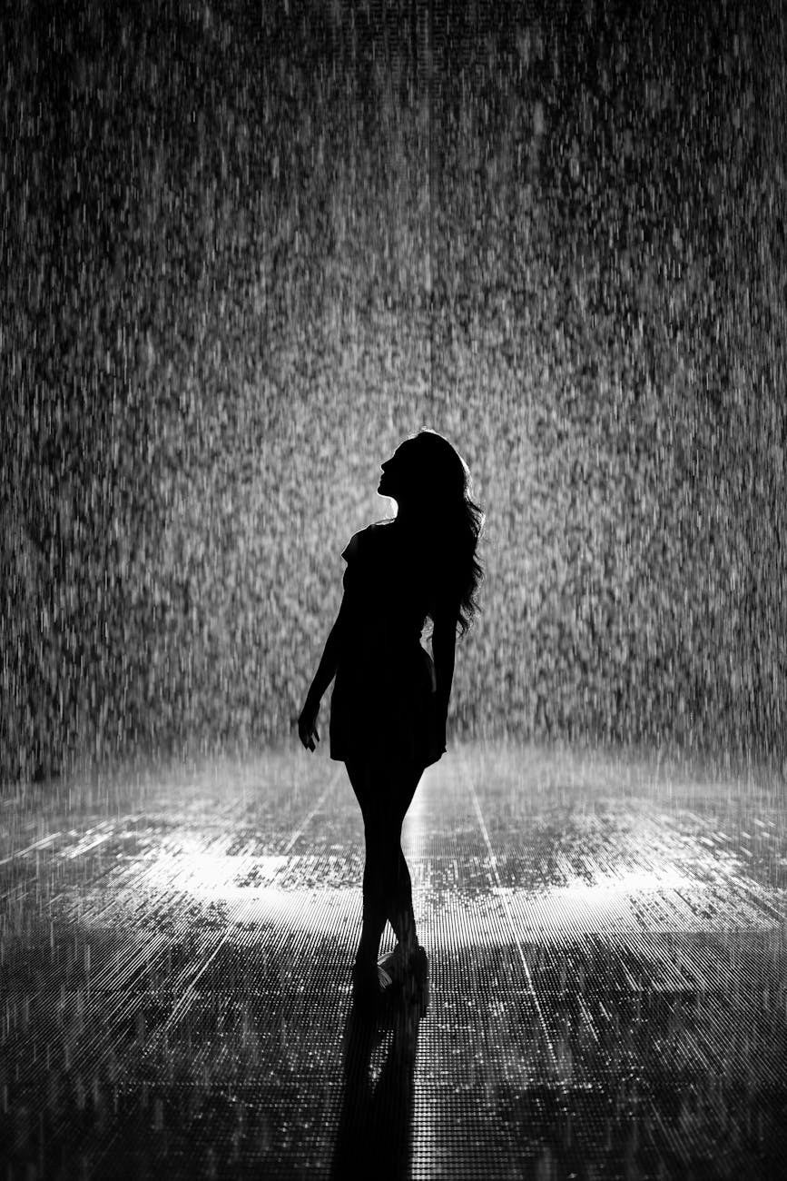 Artistic silhouette of a woman enjoying the rain. Backlit and dramatic. Artistic silhouette of a woman enjoying the rain. Backlit and dramatic.