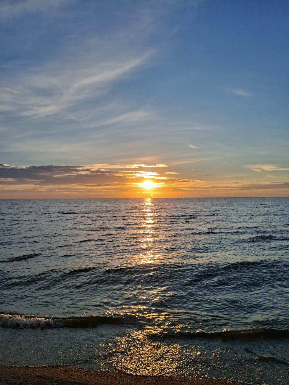 A peaceful sunset over the ocean with gentle waves and a vibrant sky.