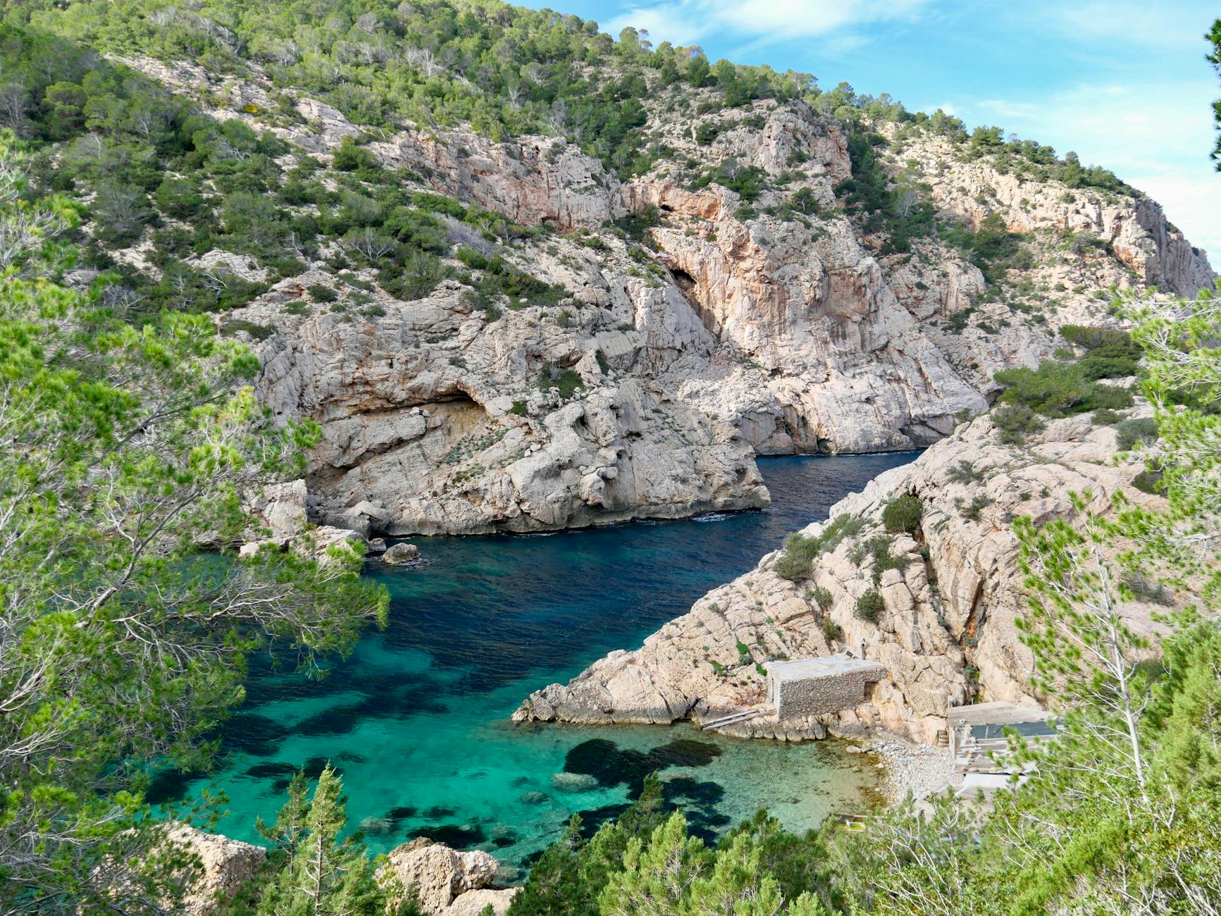 Blick in wildromantische Bucht mit Bootsschuppen auf Ibiza