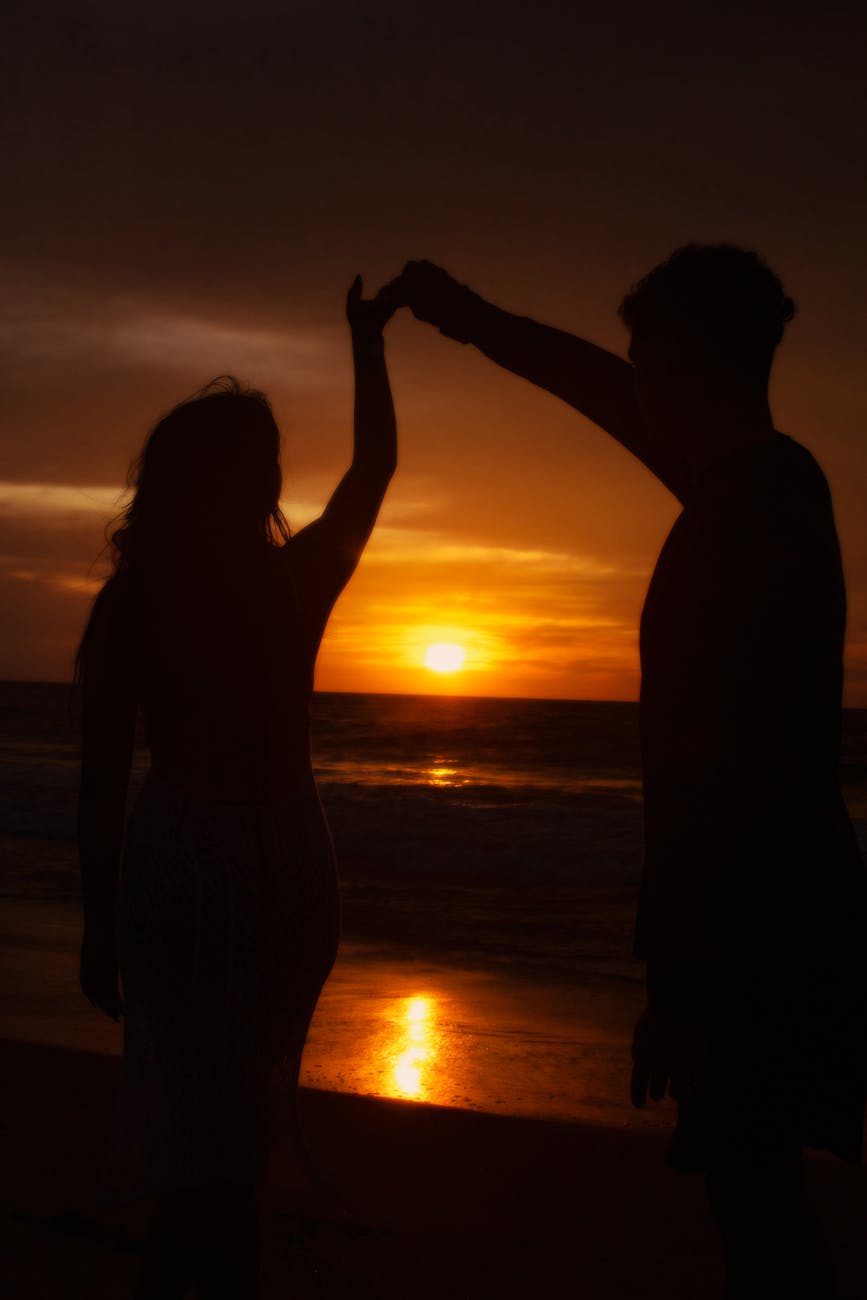 Silhouette of a couple dancing on a beach during sunset, evoking a sense of romance and tranquility.