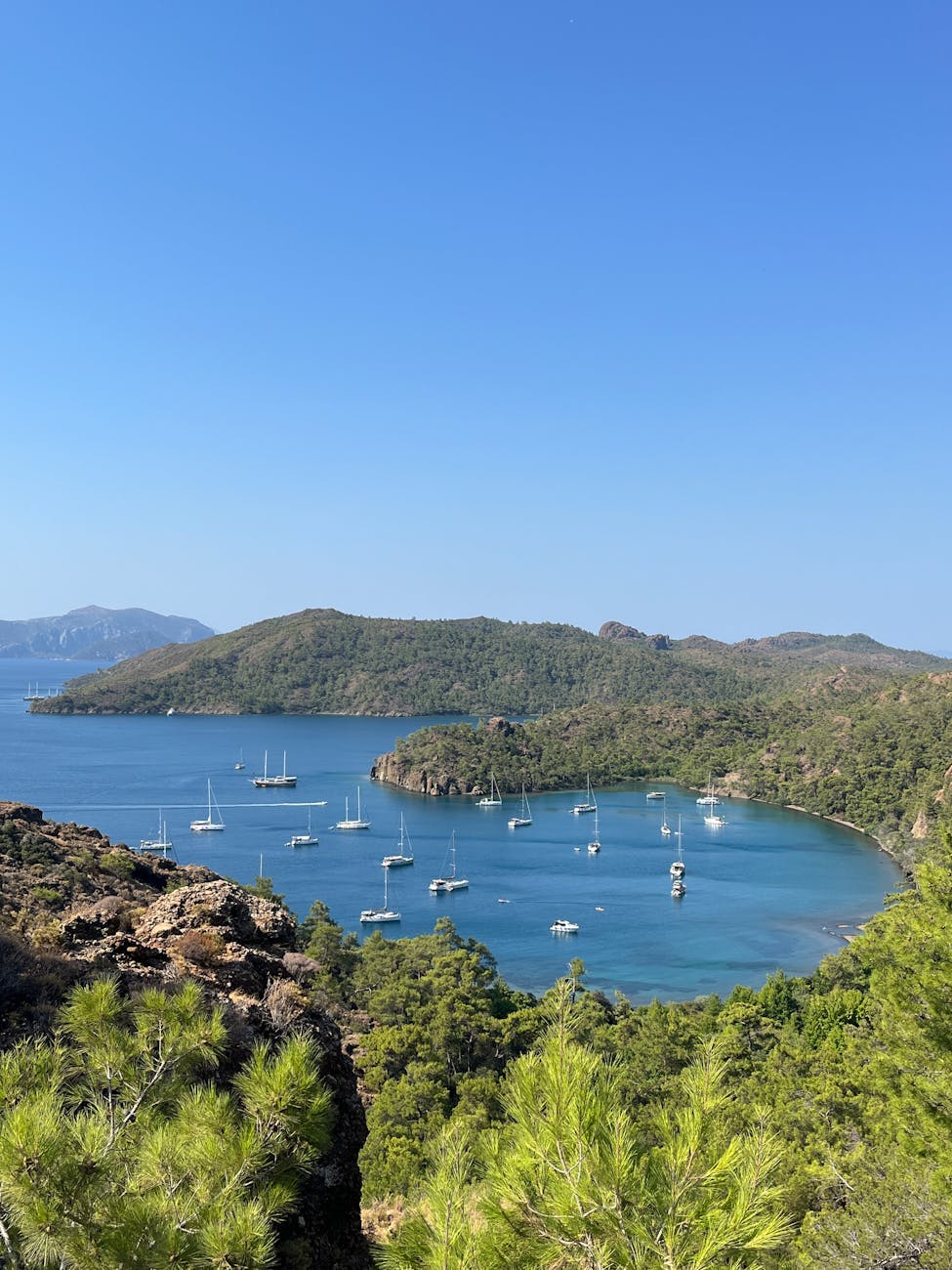 A breathtaking aerial view of a serene coastal bay dotted with sailboats and lush green hills. A breathtaking aerial view of a serene coastal bay dotted with sailboats and lush green hills.