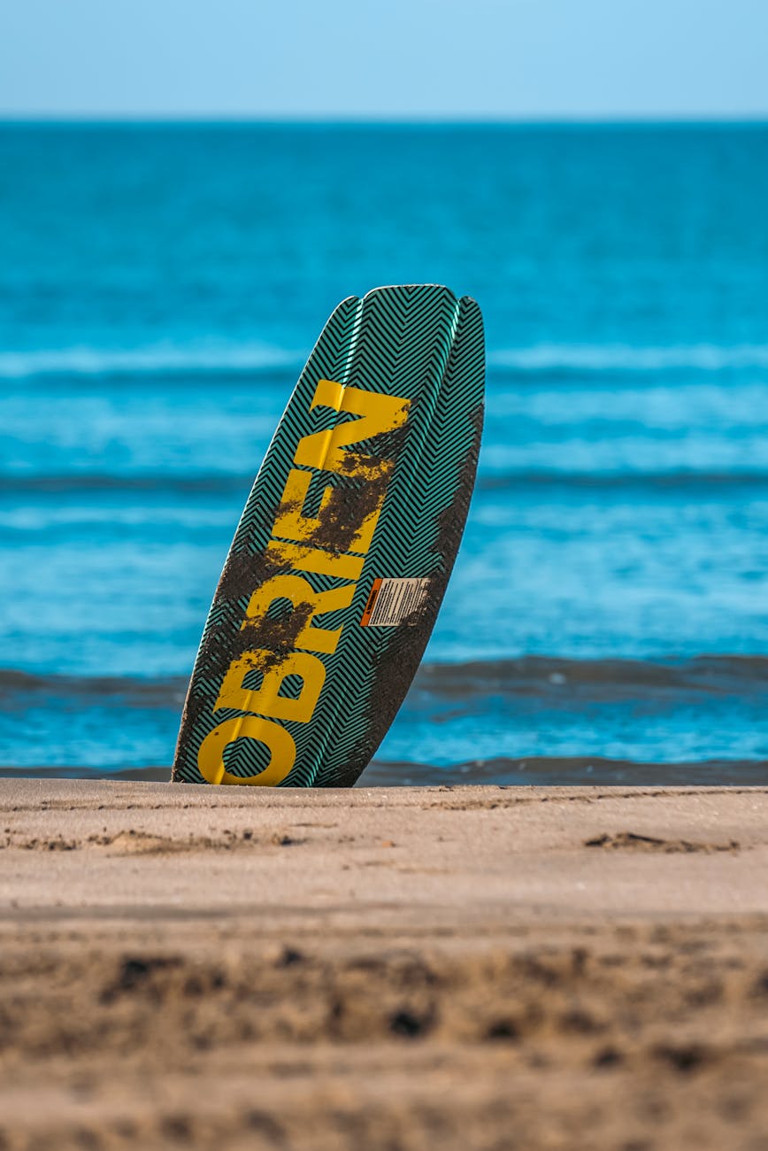 A surfboard stands upright on the sandy beach of Antalya, Türkiye, against a backdrop of the turquoise sea. A surfboard stands upright on the sandy beach of Antalya, Türkiye, against a backdrop of the turquoise sea.