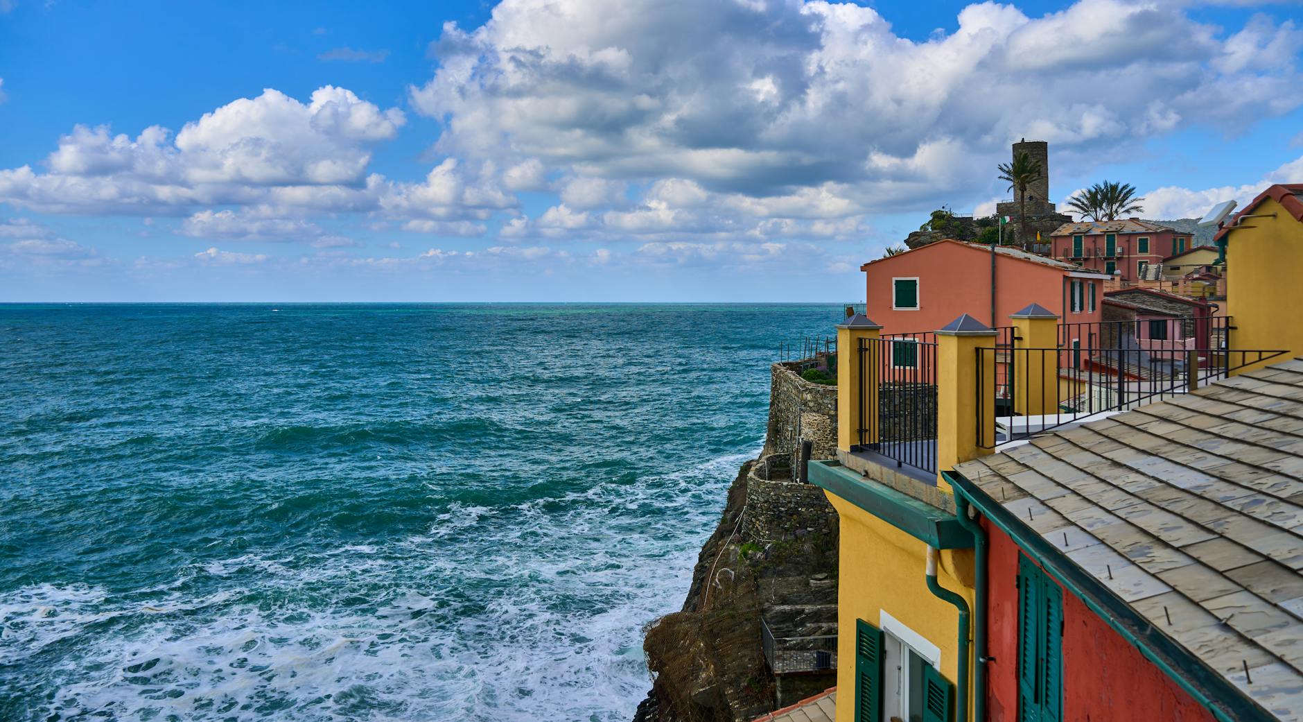 Scenic view of vibrant houses along the picturesque coastline with blue ocean waves under a cloudy sky.