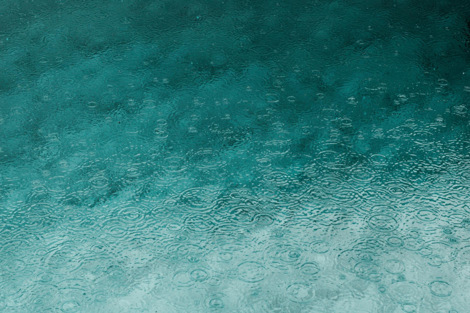 Serene teal water surface with ripples and raindrops, perfect for backgrounds. Serene teal water surface with ripples and raindrops, perfect for backgrounds.