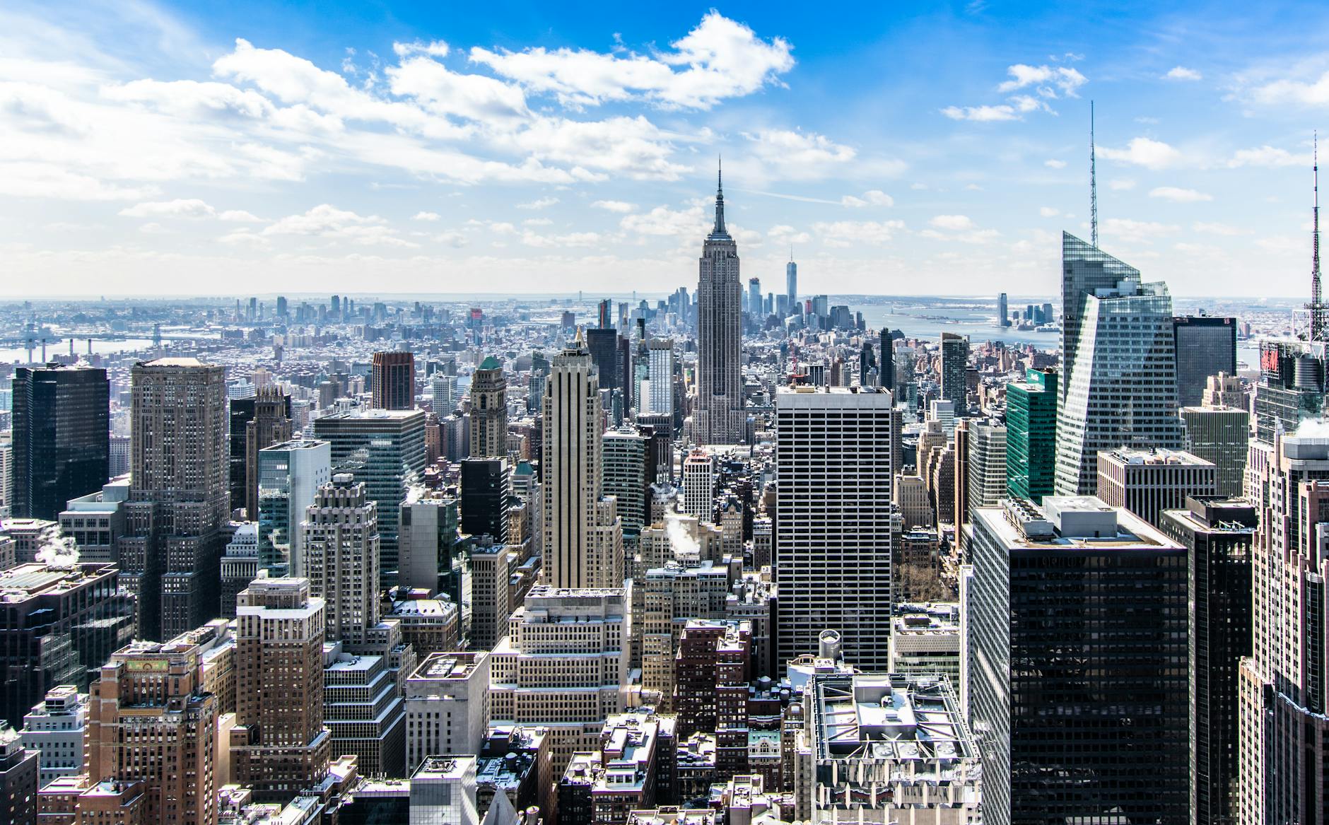 A stunning aerial view of New York City’s skyline featuring the iconic Empire State Building under a bright blue sky.