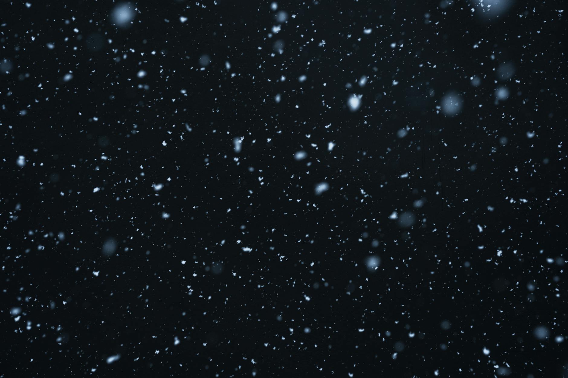 A mesmerizing view of snowflakes falling against a dark, starry night sky. A mesmerizing view of snowflakes falling against a dark, starry night sky.