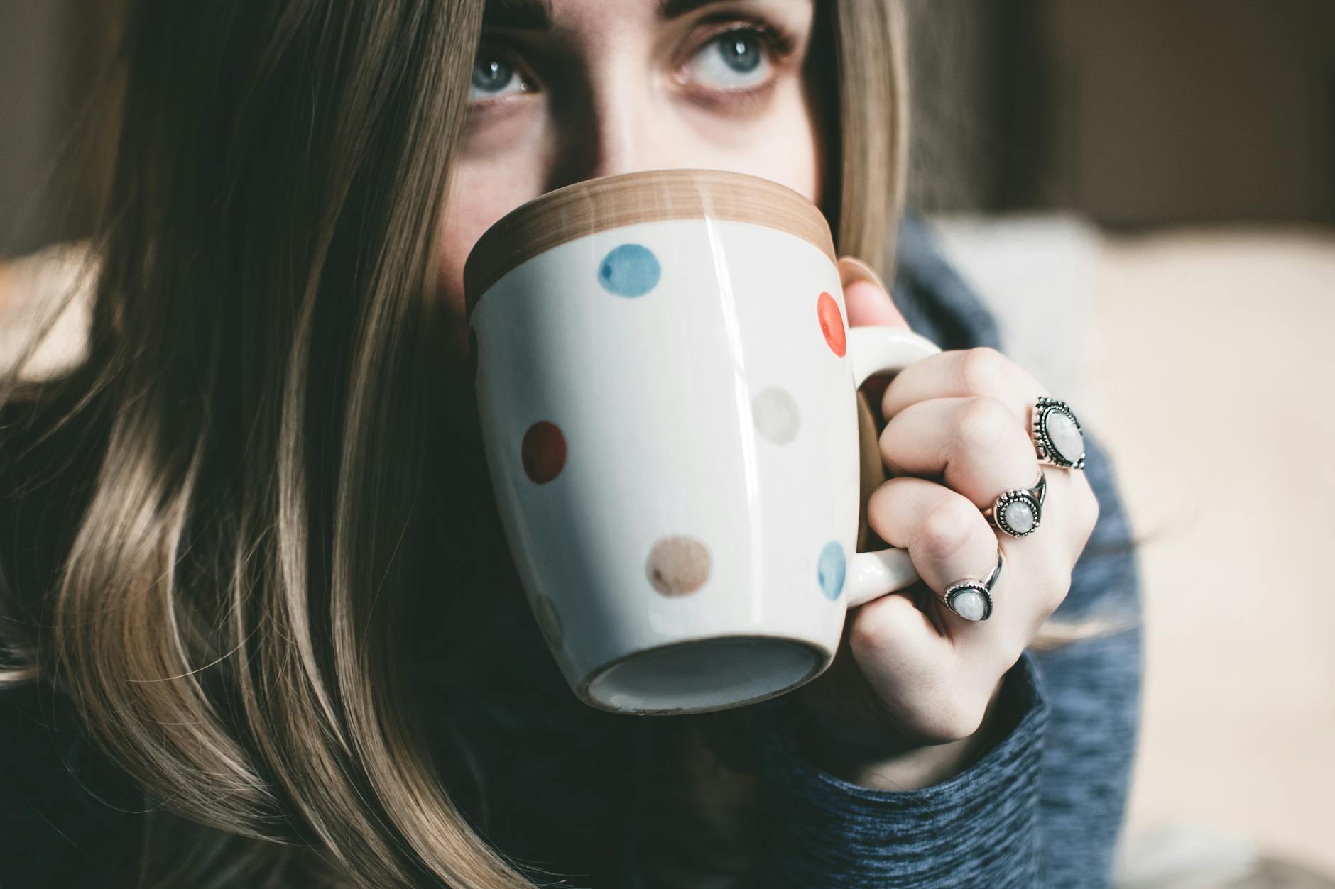 A woman enjoys a cozy moment sipping coffee from a polka dot mug indoors. A woman enjoys a cozy moment sipping coffee from a polka dot mug indoors.