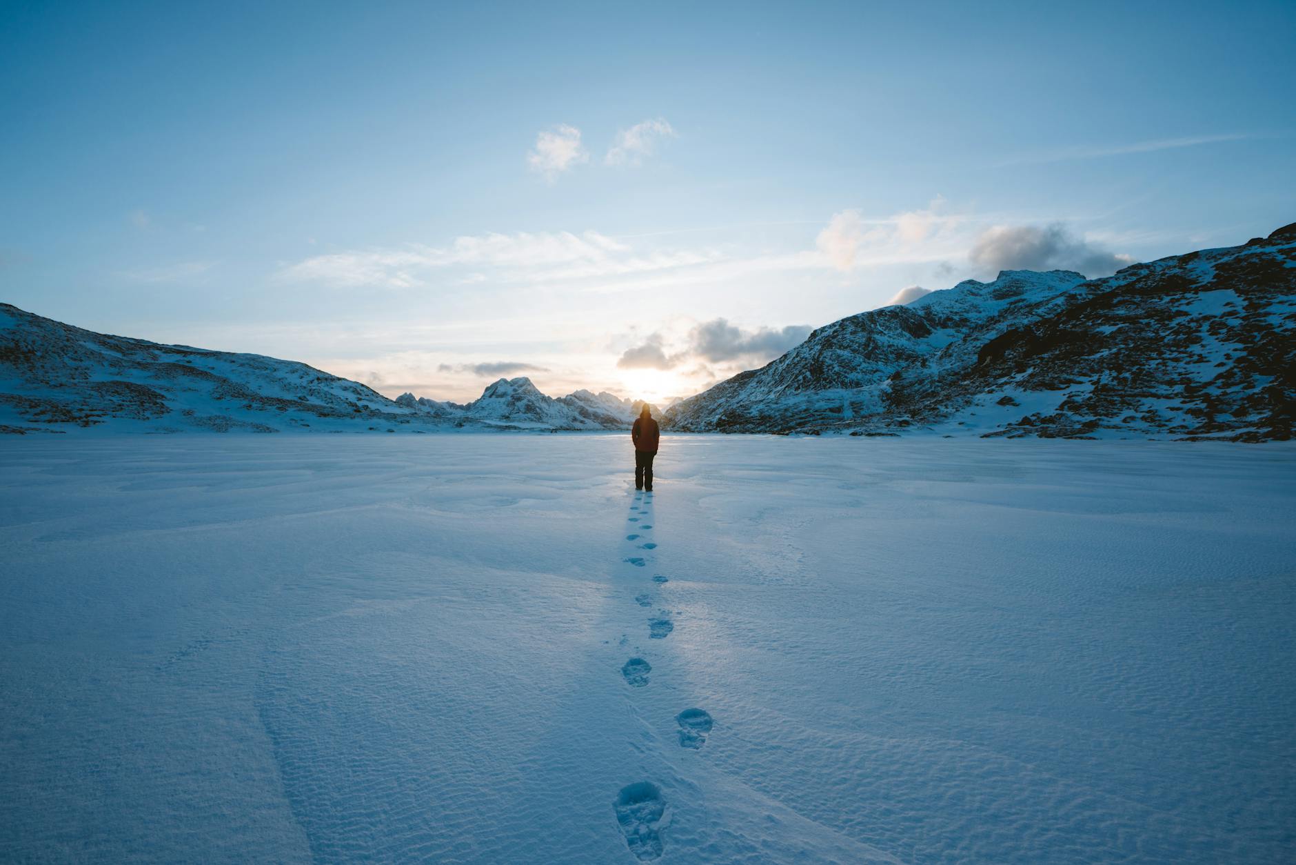 A person walking alone on a snowy landscape in Flakstad, Norway during winter.