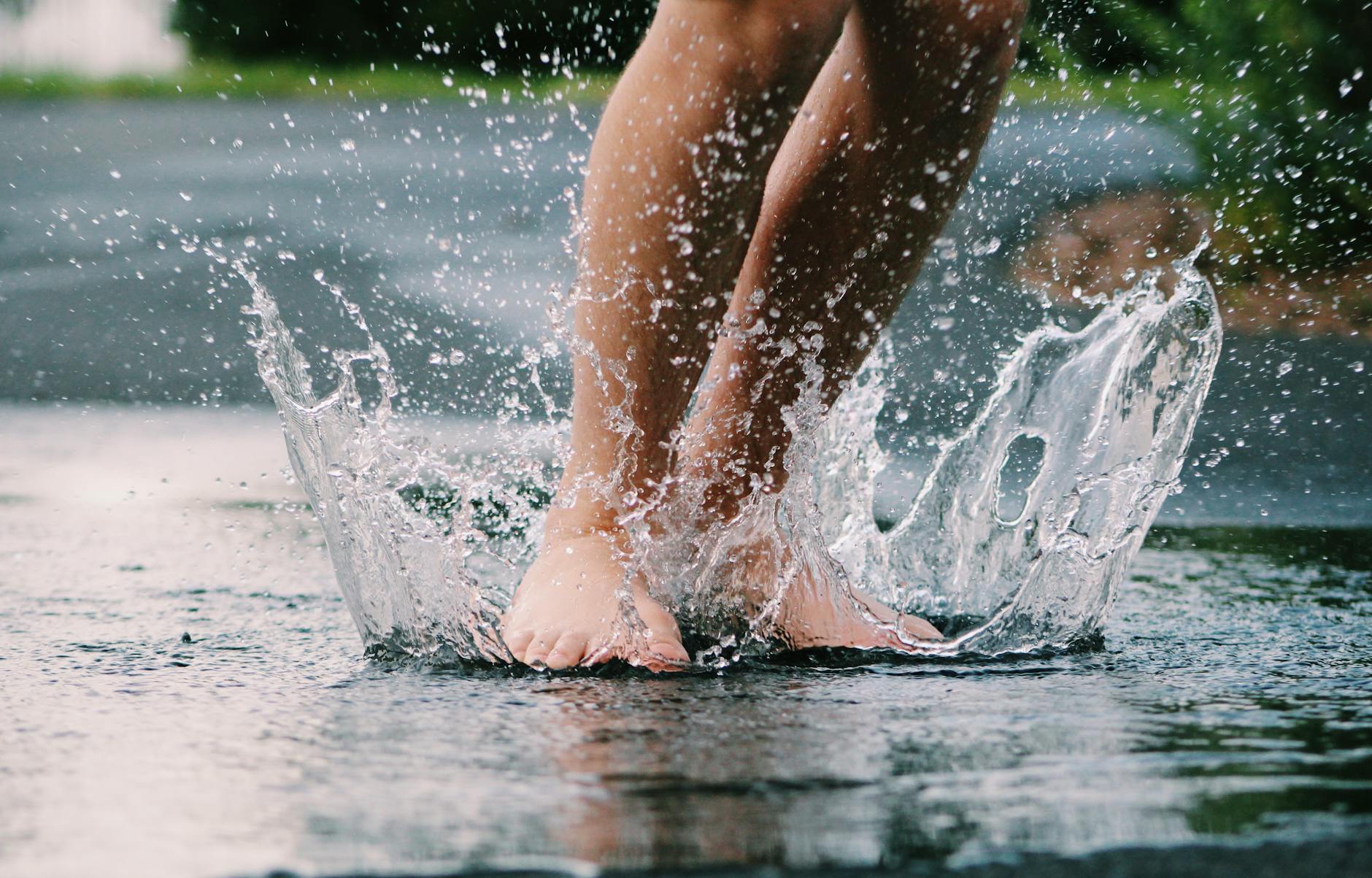 Bare feet splashing in a puddle, capturing the joy of a rainy day outdoors. Bare feet splashing in a puddle, capturing the joy of a rainy day outdoors.