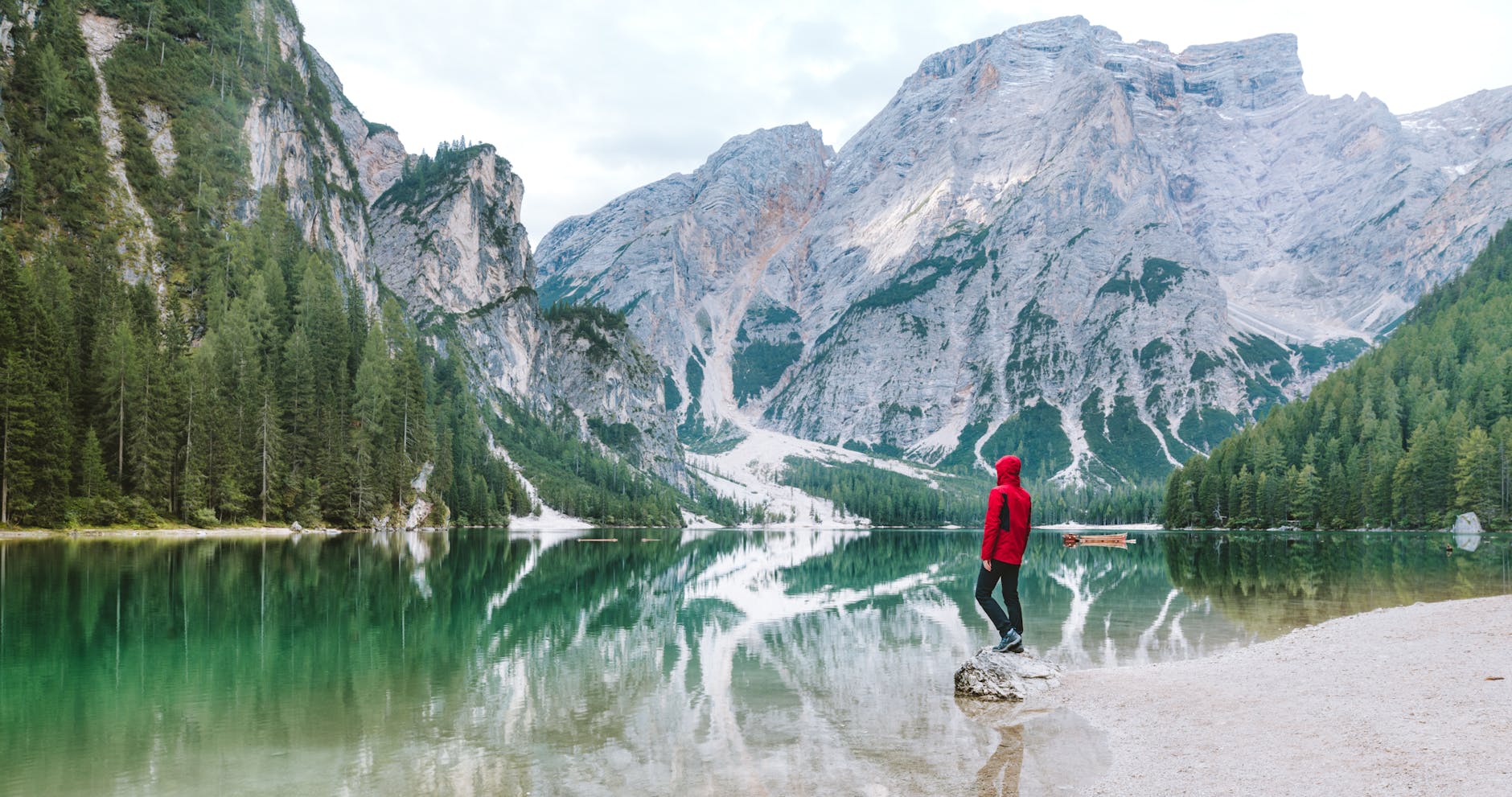 Person standing by the scenic Lake Braies with majestic Dolomite mountains reflected in the water. Person standing by the scenic Lake Braies with majestic Dolomite mountains reflected in the water.