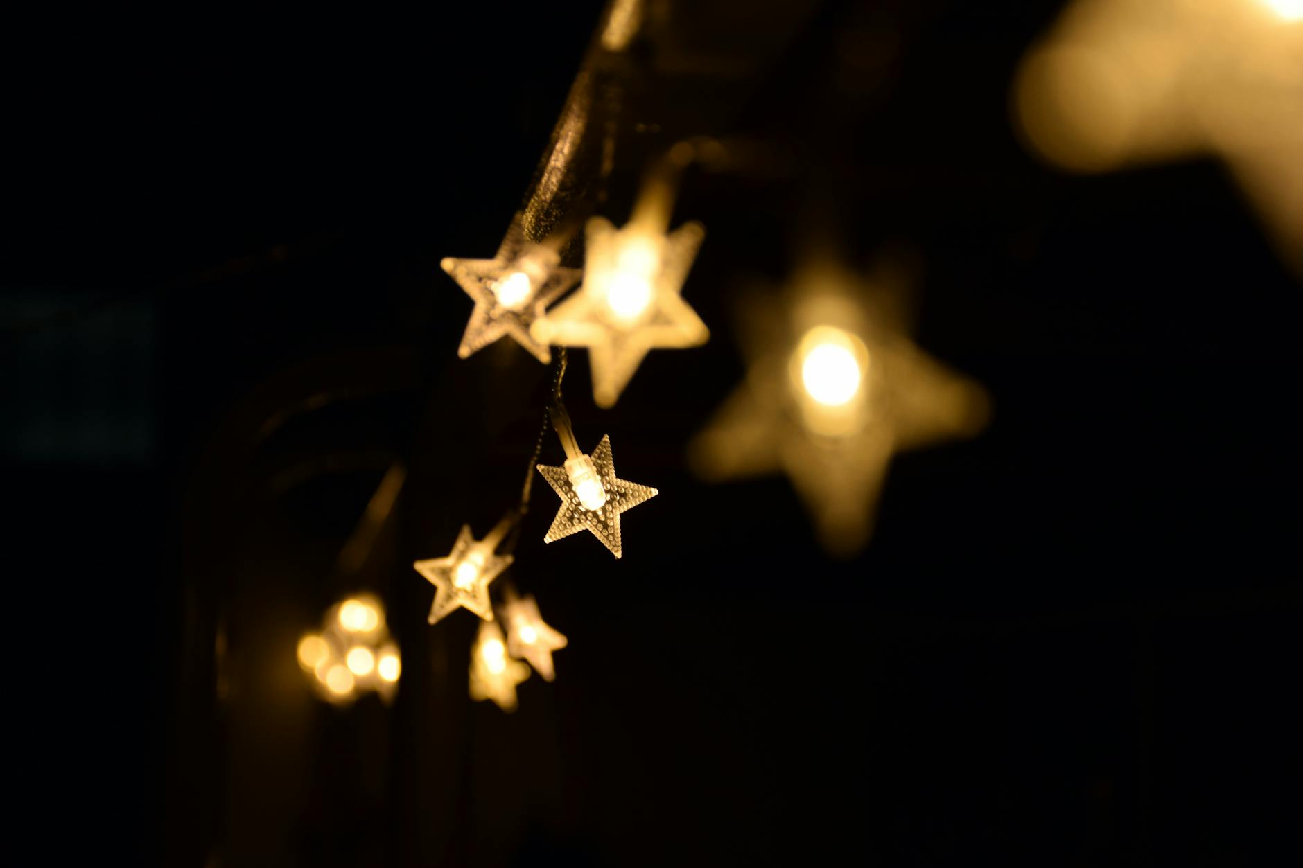 Warm star-shaped fairy lights hanging elegantly in the night, creating a festive ambiance. Warm star-shaped fairy lights hanging elegantly in the night, creating a festive ambiance.