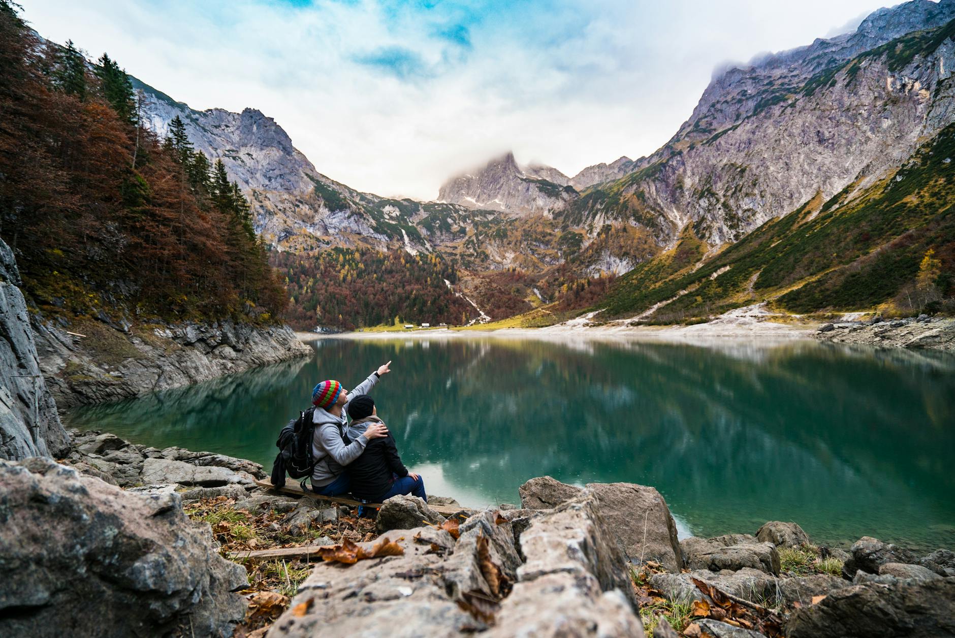 A couple enjoys a scenic view of Hallstatt Lake surrounded by mountains and fores. A couple enjoys a scenic view of Hallstatt Lake surrounded by mountains and fores.
