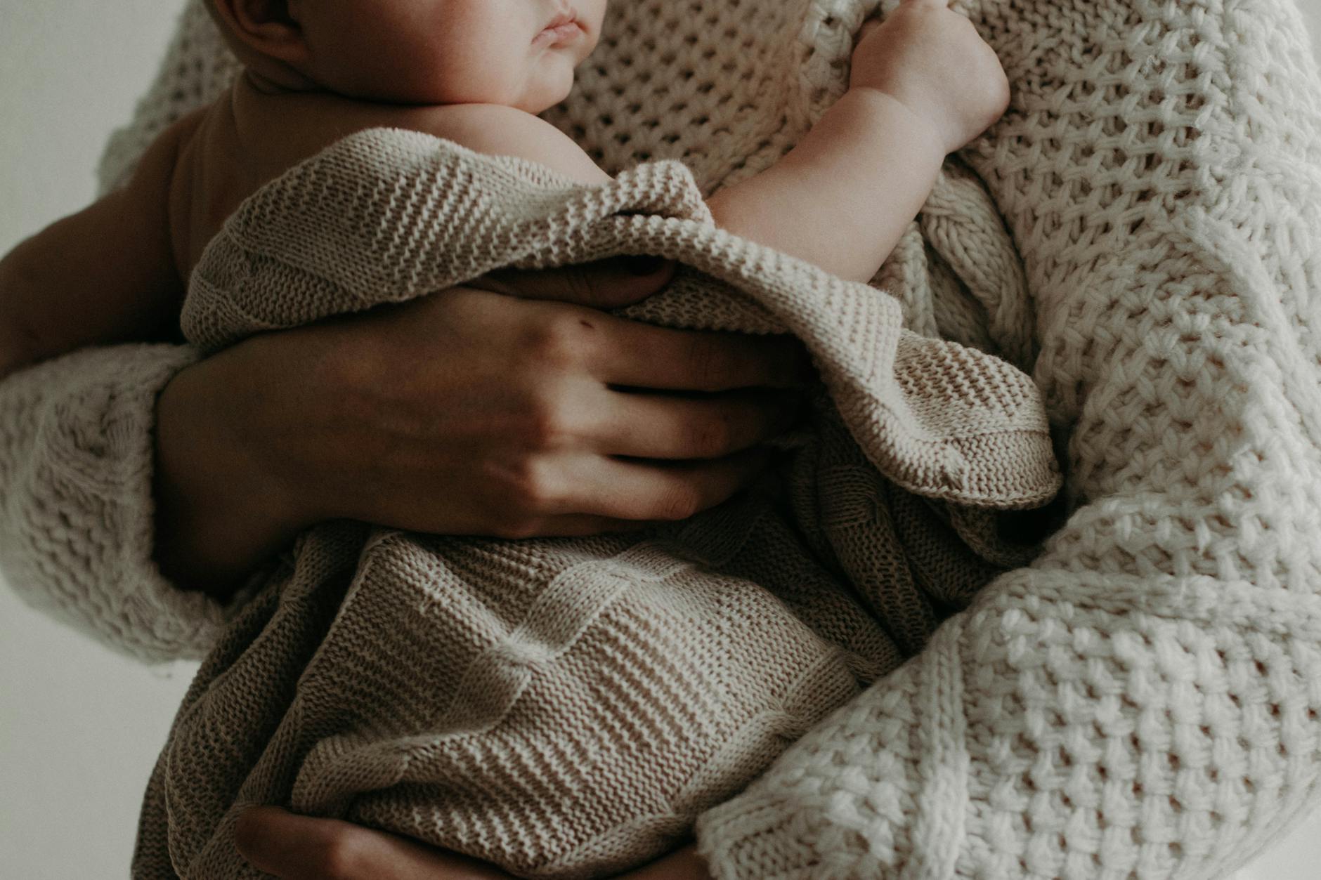 A tender moment of a mother holding her baby wrapped in a blanket, exuding warmth and care. A tender moment of a mother holding her baby wrapped in a blanket, exuding warmth and care.