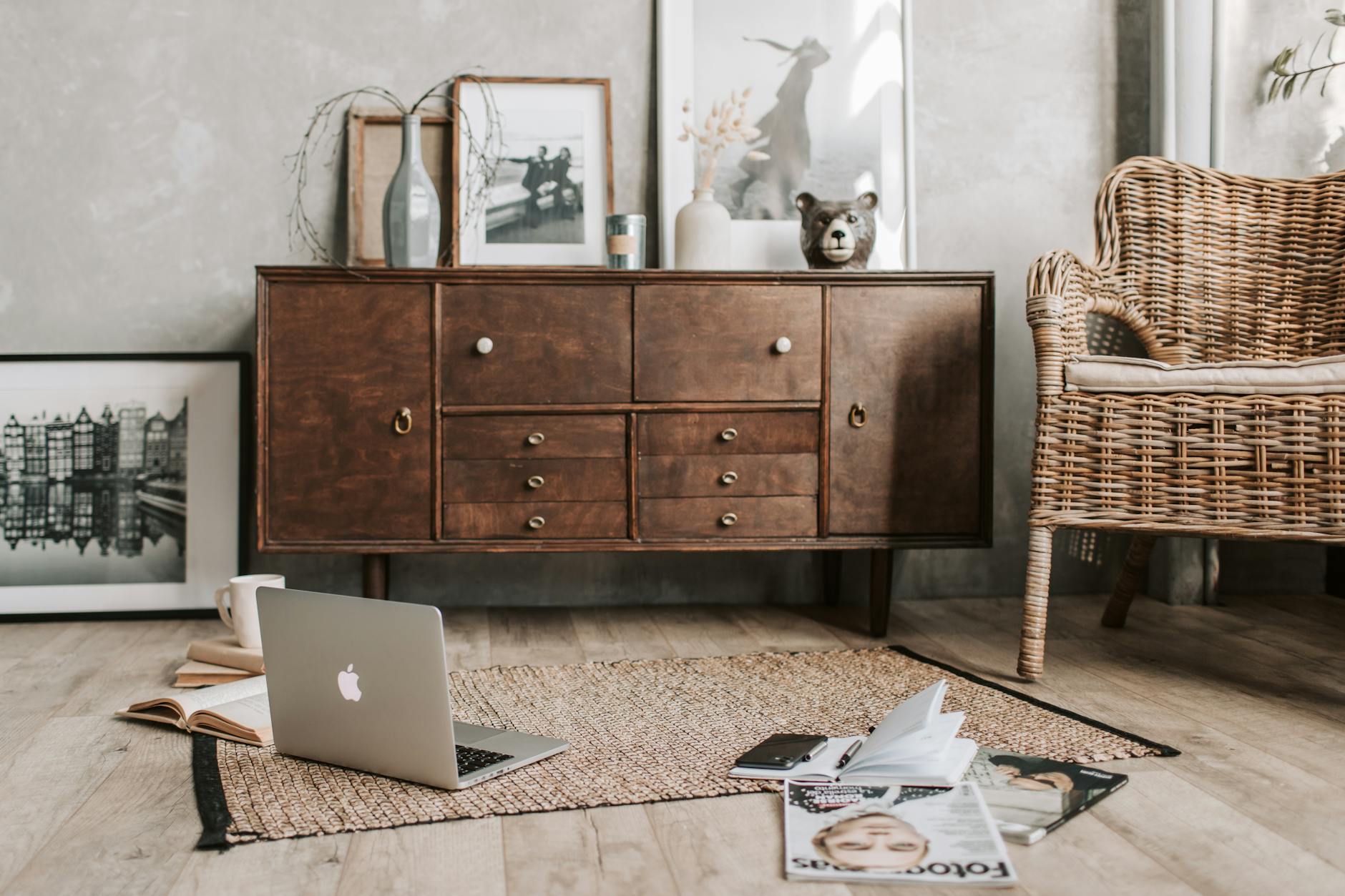 A cozy home office interior featuring a rustic wooden cabinet, wicker chair, and open laptop. A cozy home office interior featuring a rustic wooden cabinet, wicker chair, and open laptop.