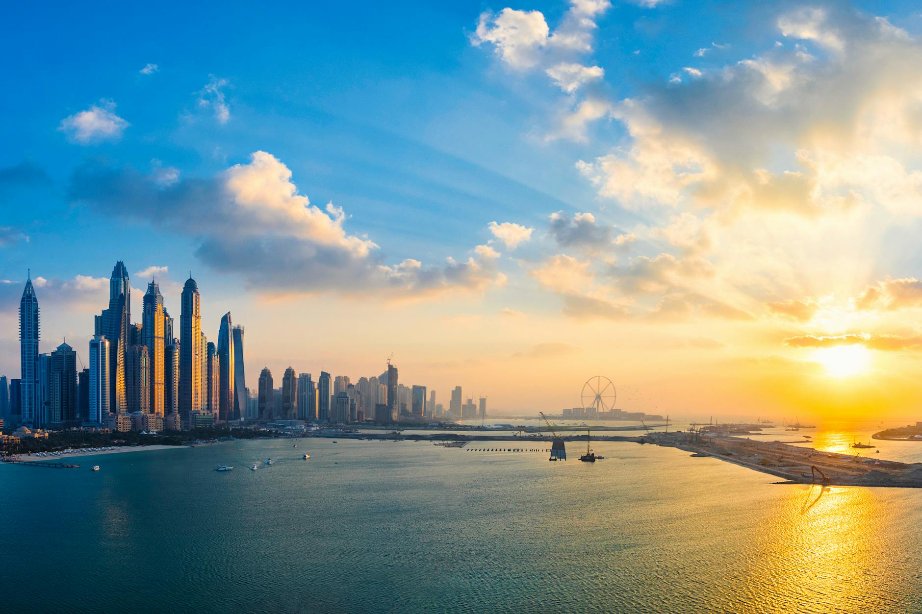 Stunning view of Dubai’s skyline and waterfront during golden hour with glowing skyscrapers reflecting on the water.