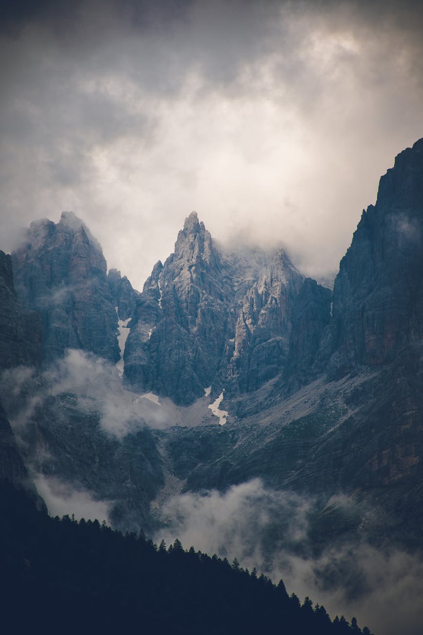 Scenic view of dramatic mountain peaks shrouded in clouds. Scenic view of dramatic mountain peaks shrouded in clouds.