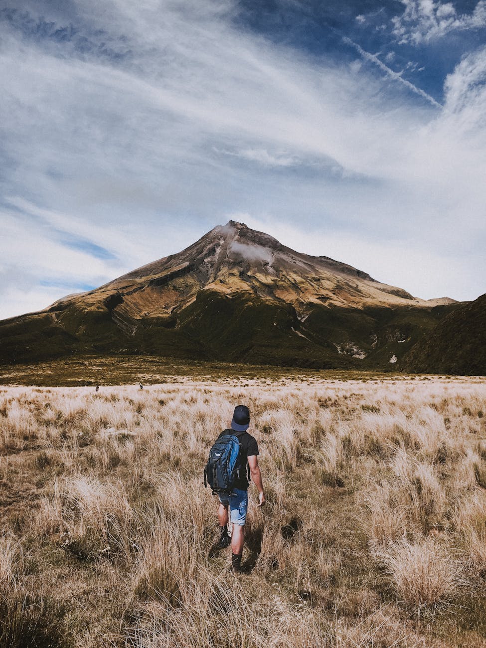 A backpacker walks towards a scenic mountain under a dramatic sky. A backpacker walks towards a scenic mountain under a dramatic sky.