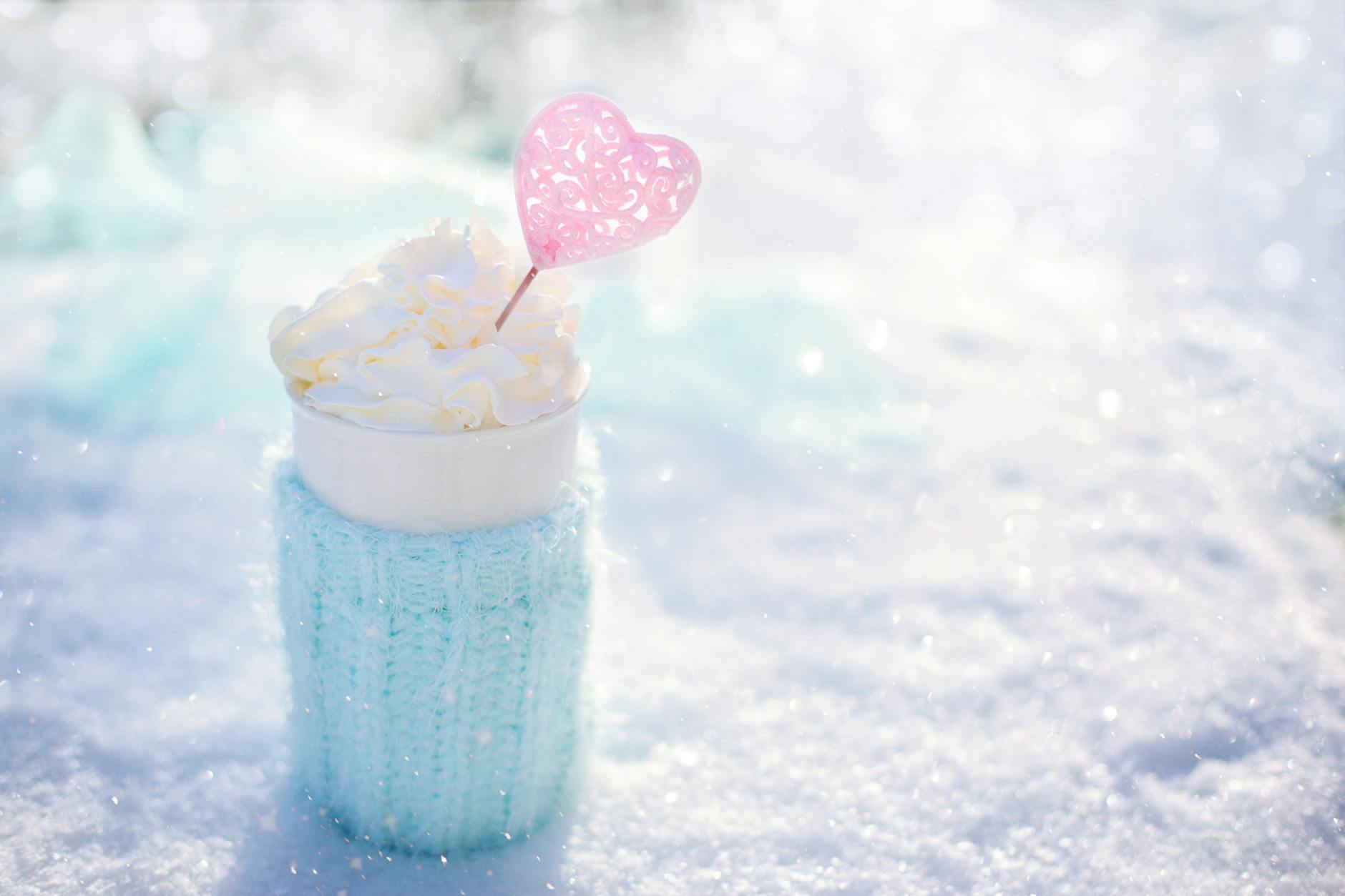 Warm beverage topped with cream in snow, perfect for winter themes. Warm beverage topped with cream in snow, perfect for winter themes.