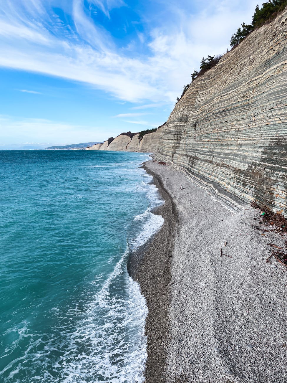 Breathtaking view of layered cliffs and turquoise waves under a vibrant blue sky. Breathtaking view of layered cliffs and turquoise waves under a vibrant blue sky.