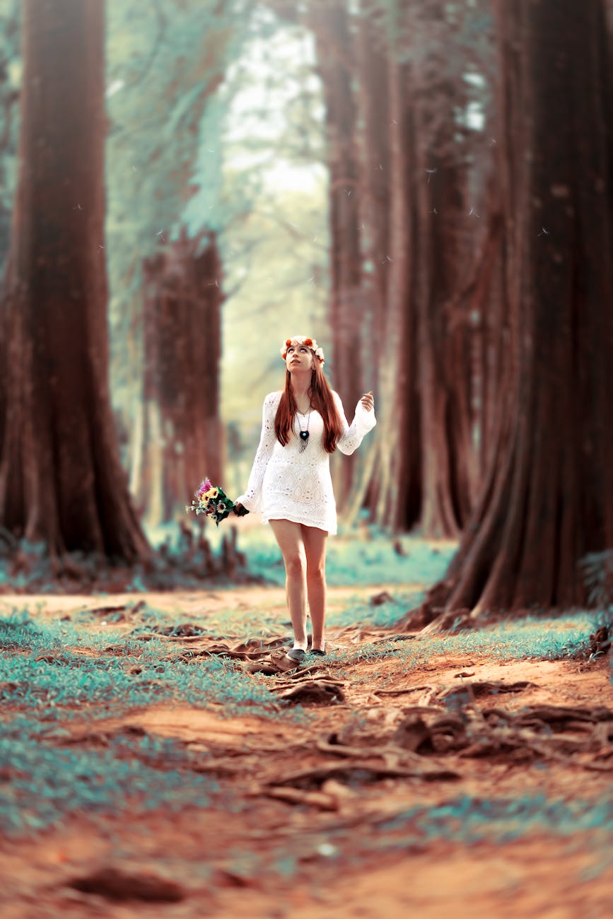 A young woman in a white dress enjoys a leisure walk in a serene forest setting.