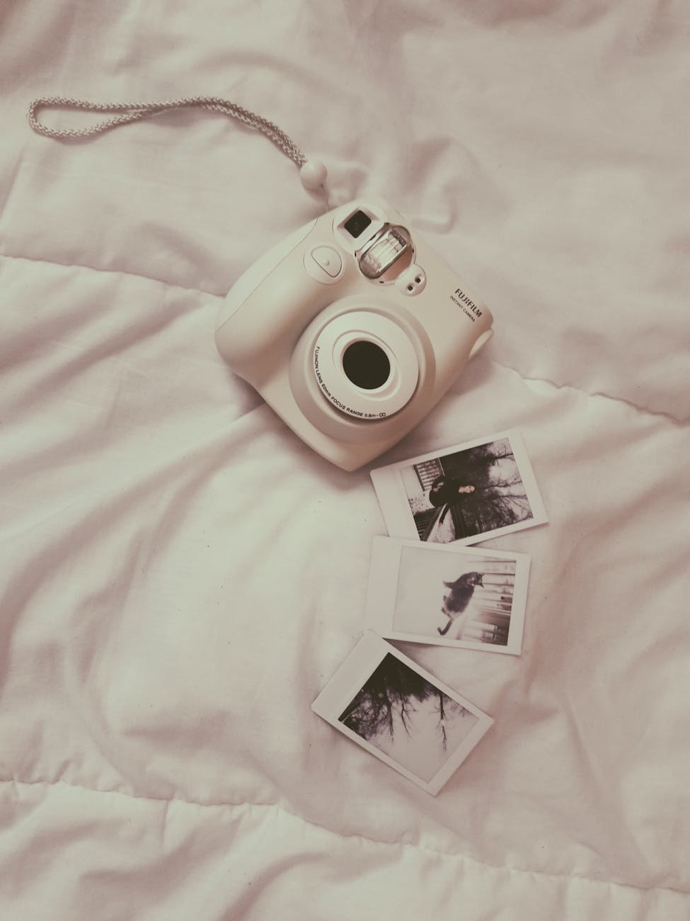 Vintage style instant camera and photos on a cozy bed, creating a relaxed and nostalgic vibe. Vintage style instant camera and photos on a cozy bed, creating a relaxed and nostalgic vibe.